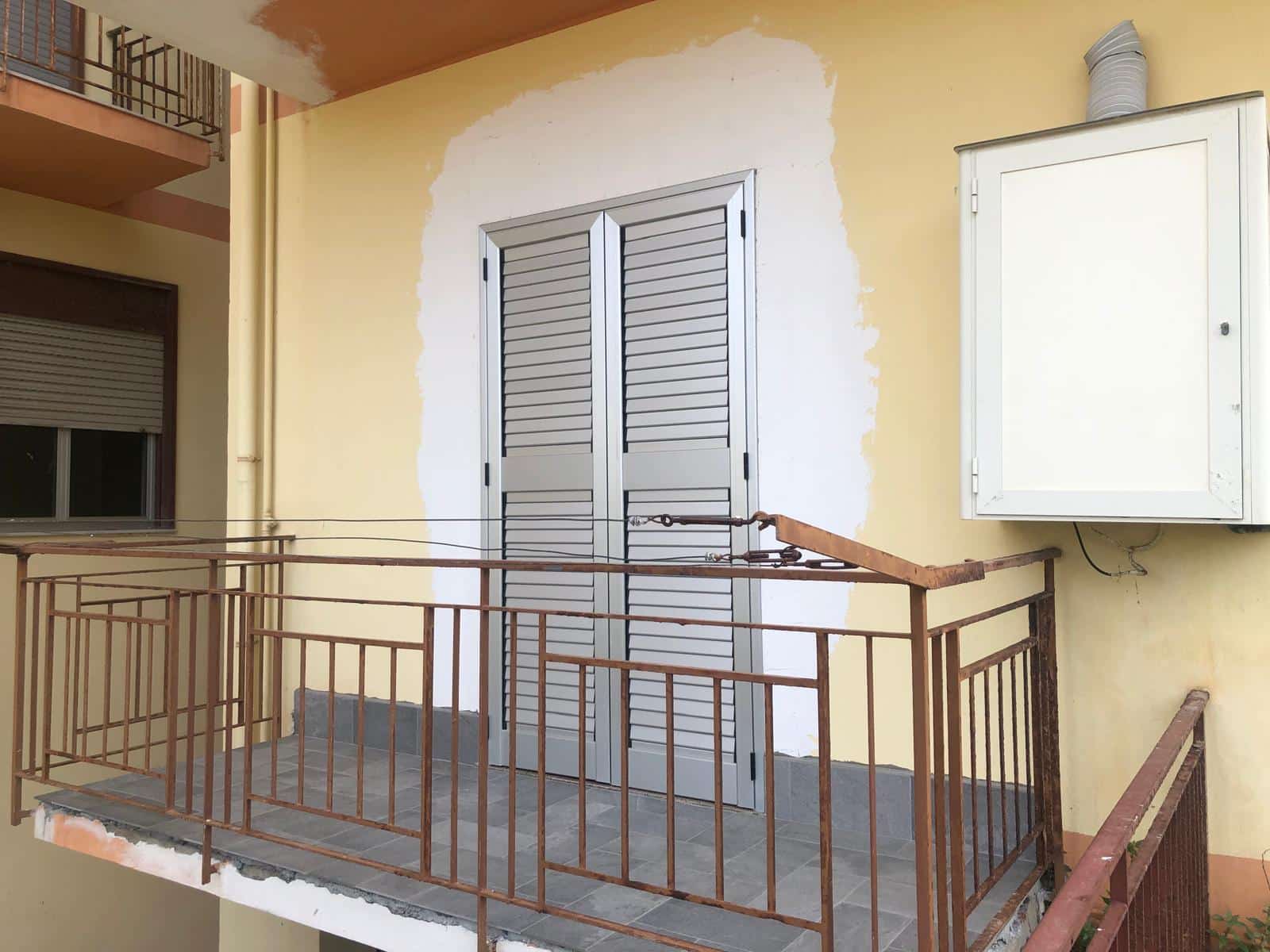 Finestra balcone in alluminio verniciato e ringhiera in ferro, situazione di ristrutturazione o manutenzione, parete della facciata in fase di riparazione.