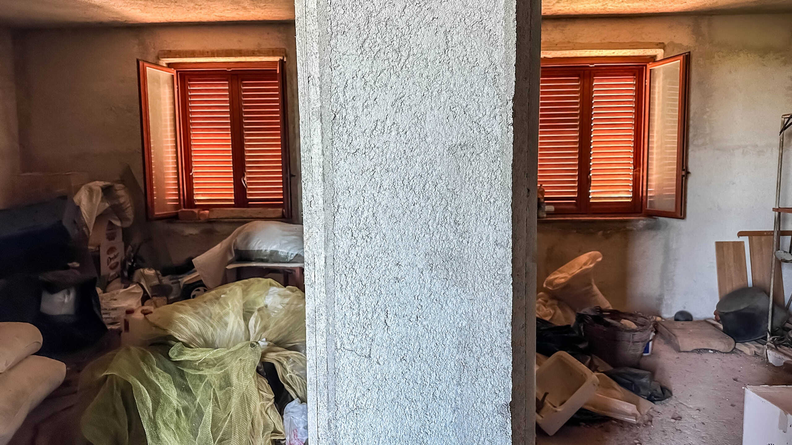 Spazi interni di una casa in fase di ristrutturazione con finestre in legno, raccolta di materiali e oggetti vari, ambiente in disordine, illuminazione naturale, rinnovamento casa, soluzioni abitative innovative.