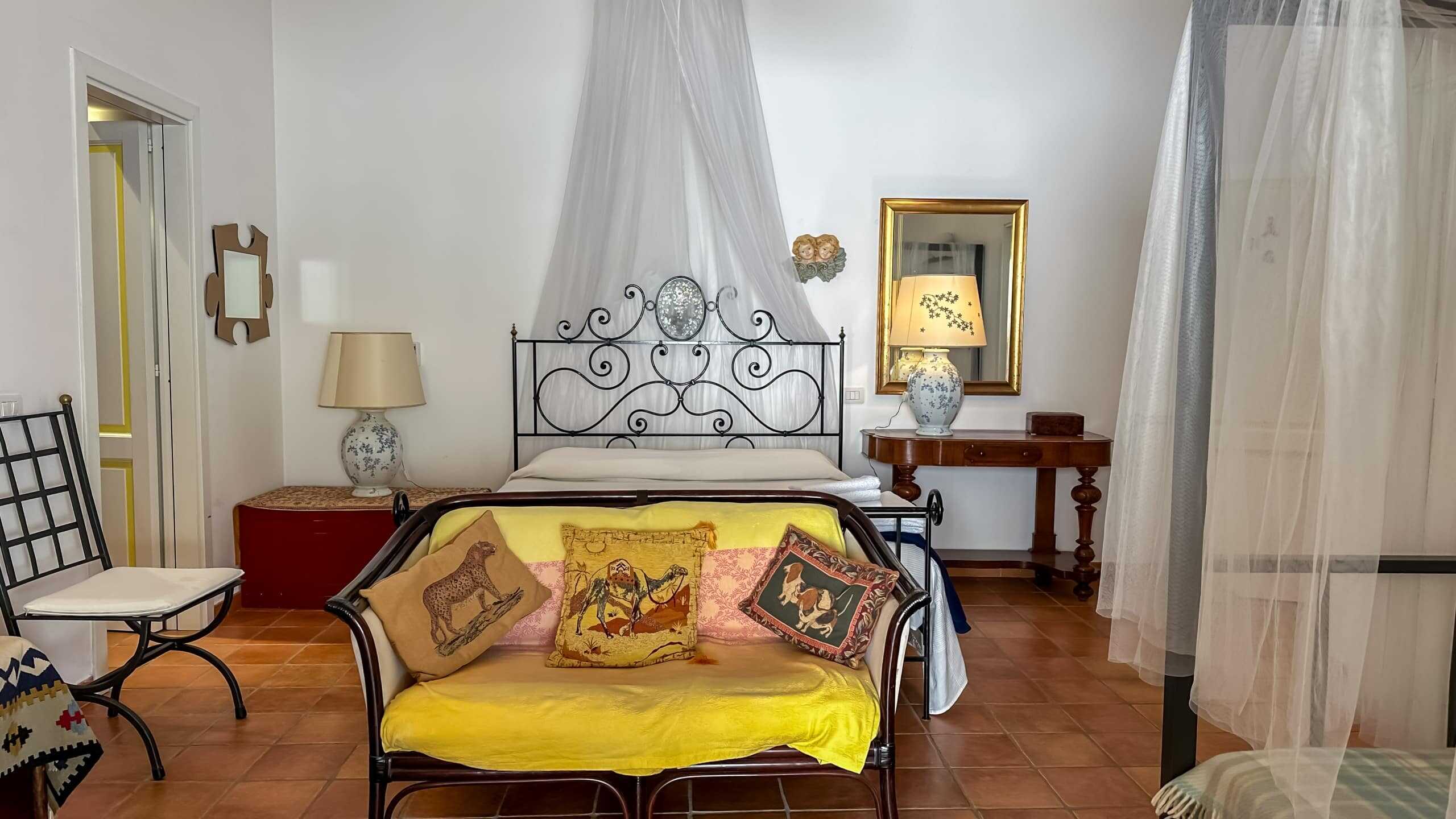 Letto con testiera in ferro battuto, decorato con tessuti e cuscini a tema animale e safari, in una camera da letto in stile classico con dettagli ricercati e atmosfera accogliente.