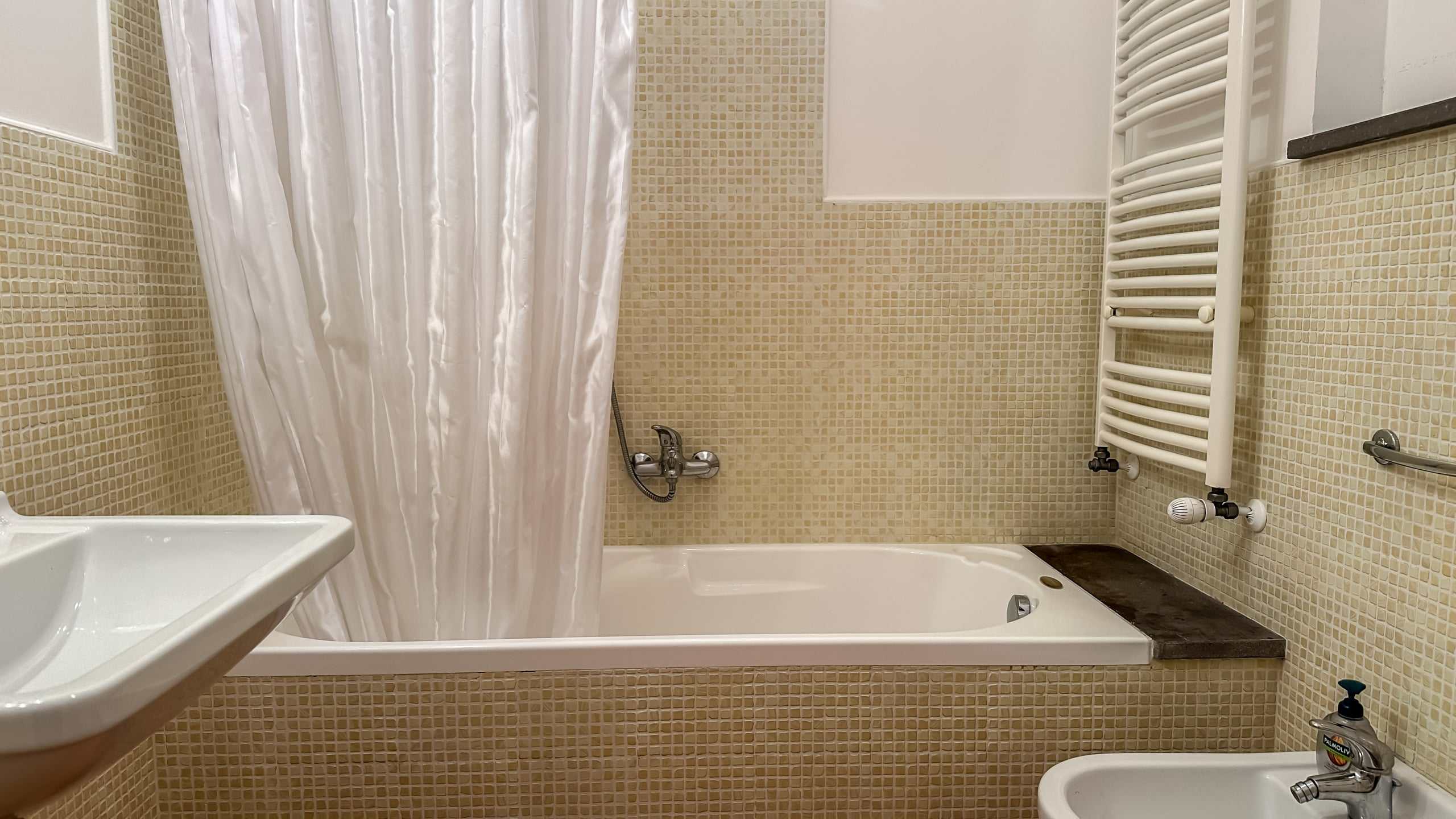 Lavabo e vasca da bagno con soffione e piastrelle beige in bagno moderno NextCasa.