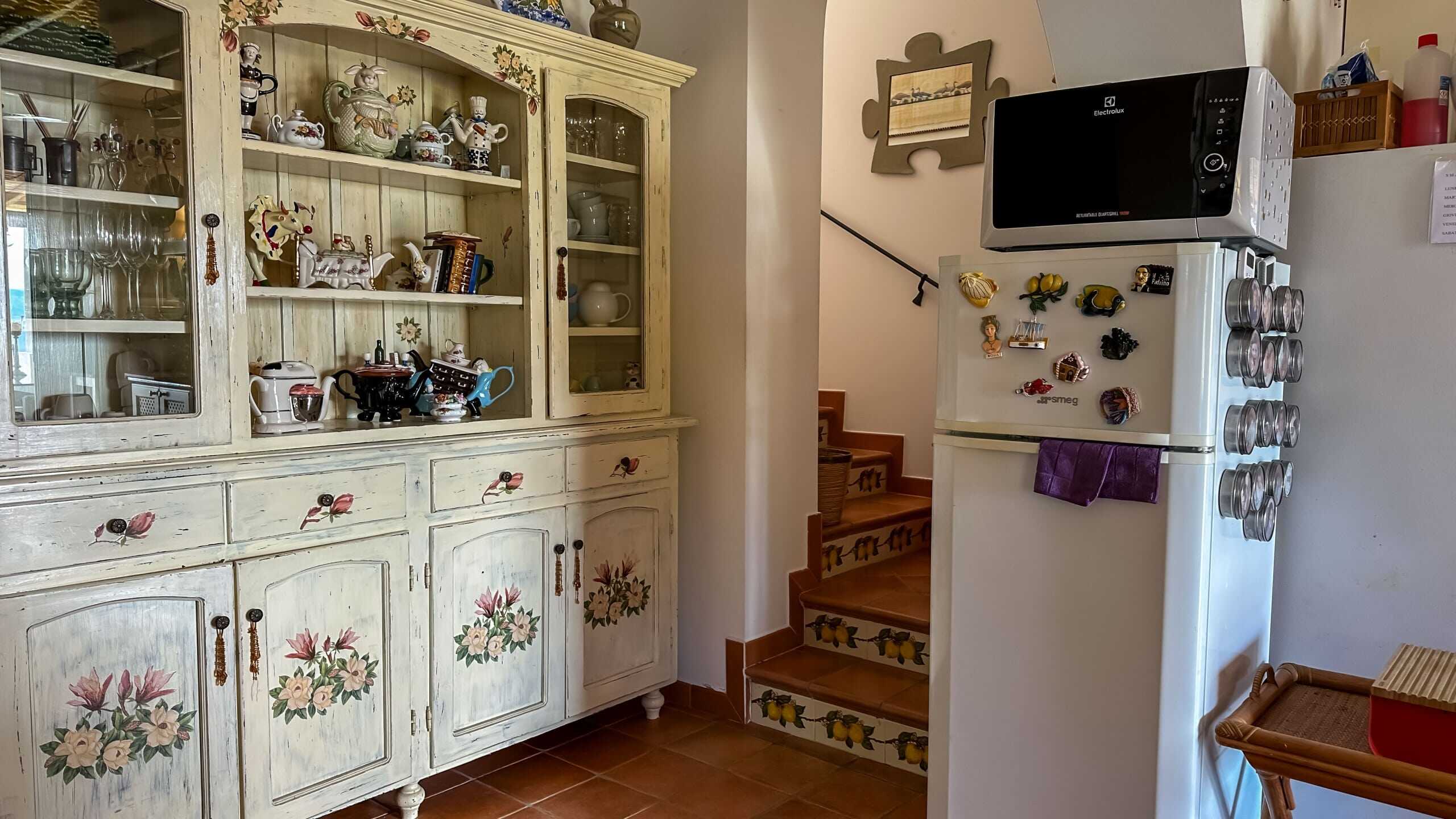Armadio rustico con decorazioni floreali, cucina classica in stile country, mobile porta oggetti in legno dipinto a mano, ideale per case di campagna, arredamento accogliente, dettagli vintage, ambiente domestico caloroso, NextCasa.