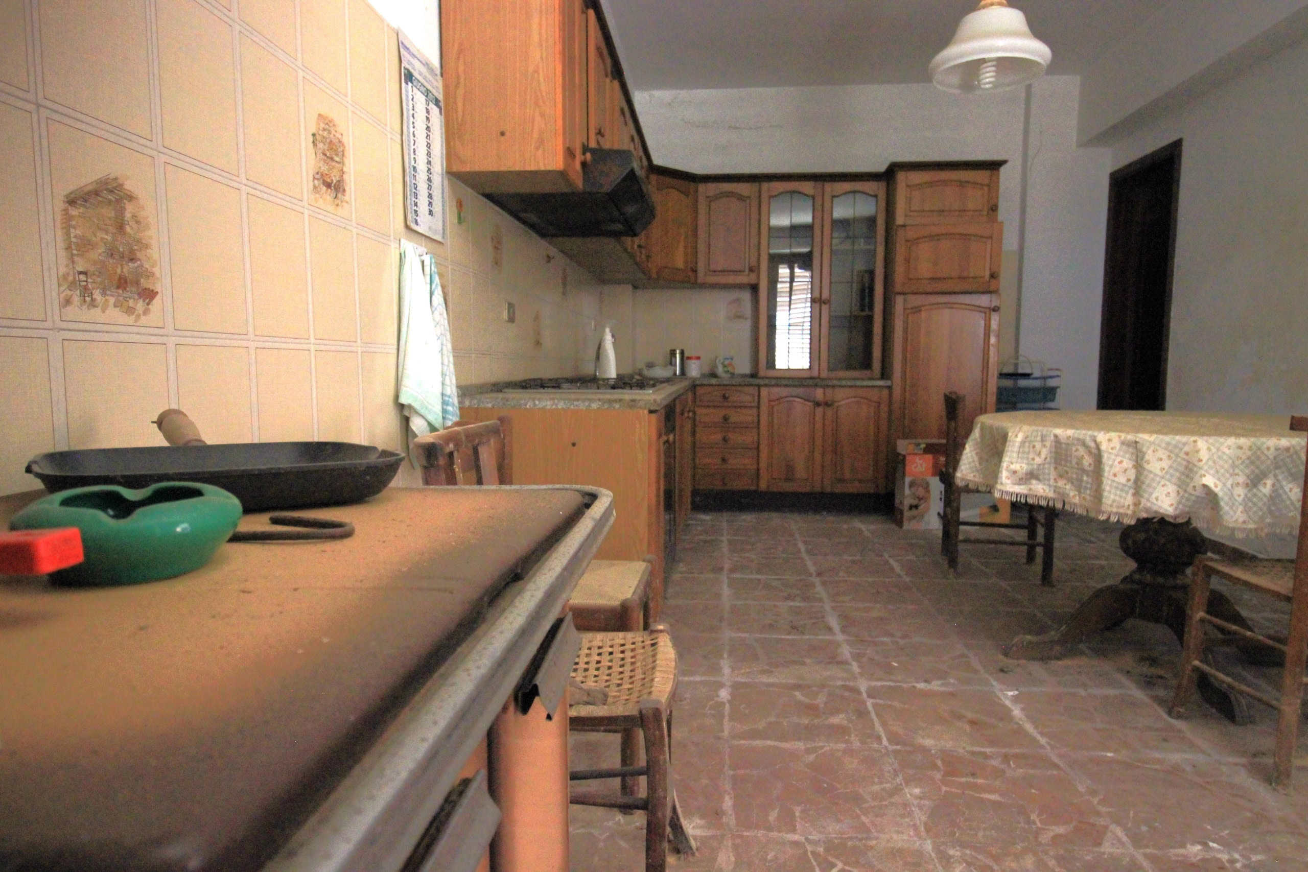 Pentola su tavolo cucina rustica in legno con mobili in muratura e pavimento in pietra.