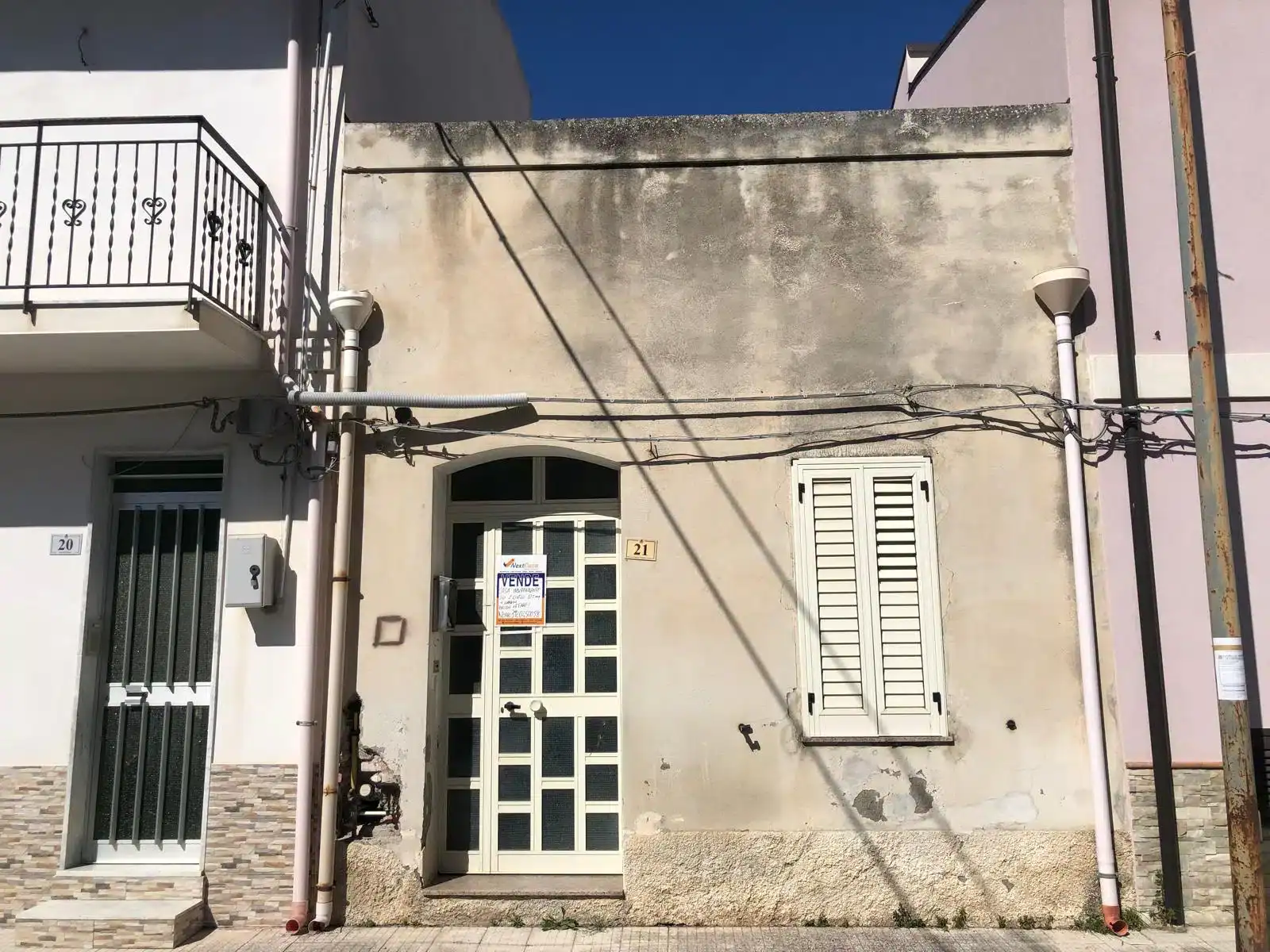 Facciata di una casa indipendente in vendita a Milazzo, con porta d'ingresso e finestra con persiana, in zona urbana.