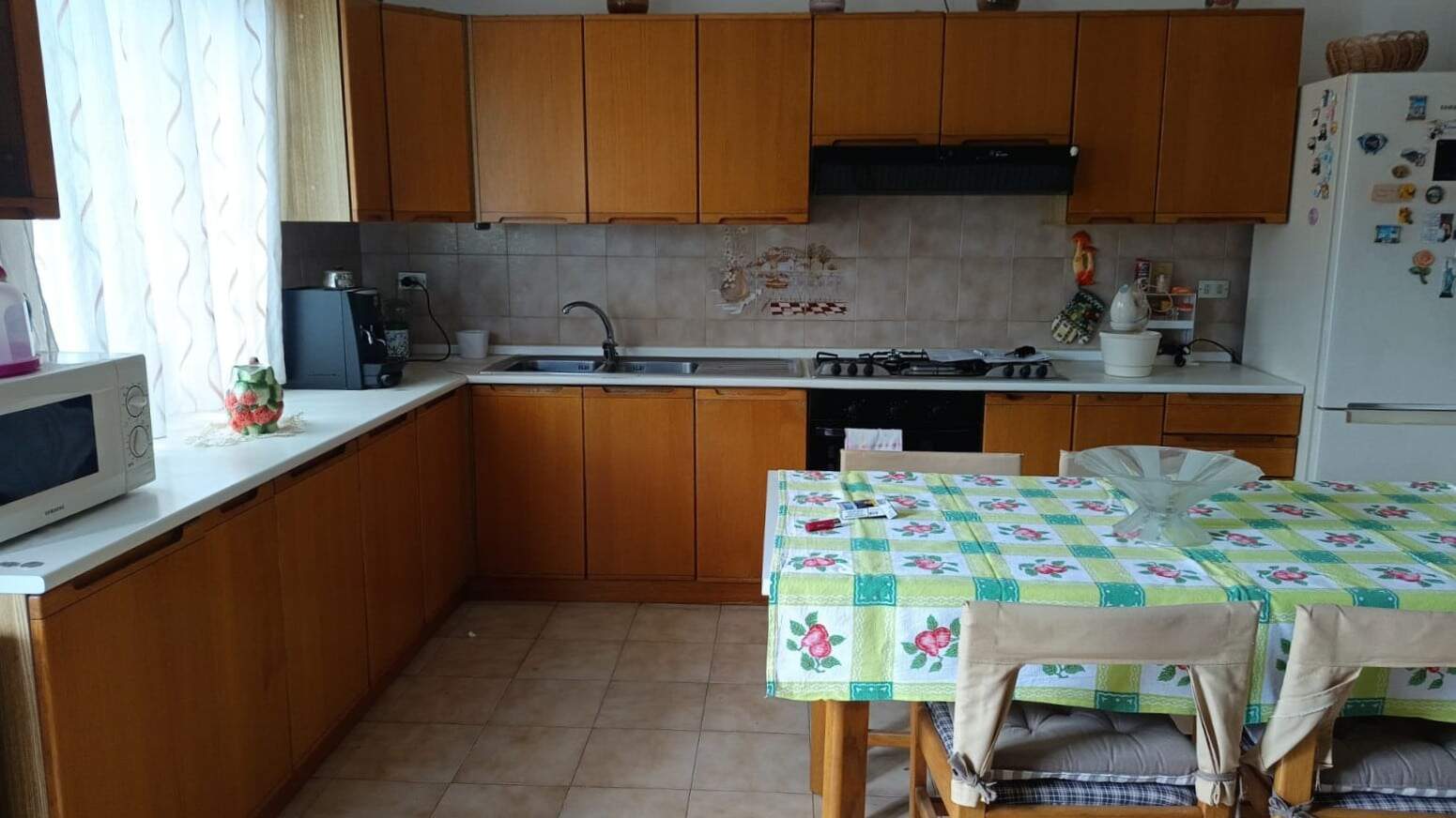 Energia e comfort in cucina con arredi in legno, elettrodomestici moderni e spaziosa zona pranzo. Ideale per creare un ambiente funzionale e accogliente nella tua casa.