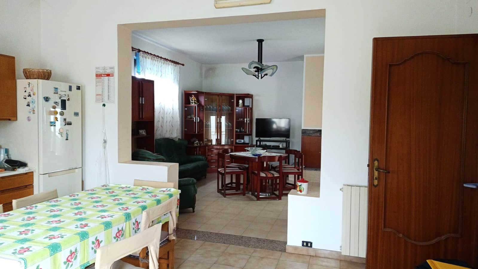 Finestra che guarda la zona soggiorno e pranzo di un appartamento con mobili in legno, soggiorno con divani e televisore, ambiente luminoso e accogliente, ideale per vivere in tranquillità.