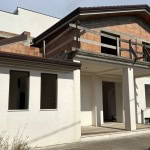 Nuova casa in costruzione con pareti bianche, finestre grandi e balcone in legno, in fase di completamento e ristrutturazione.