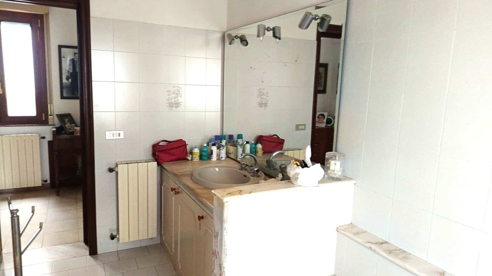 Vasche da bagno e lavabo in bagno con specchio grande, ambientazione con oggetti quotidiani e dettagli di arredamento classico, ottimale per servizi di consulenza immobiliare NextCasa.