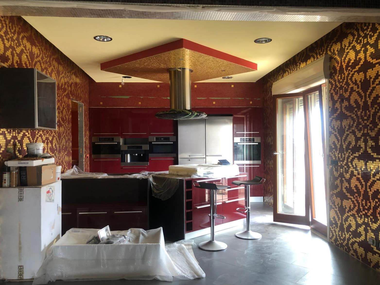 Luxurious cucina moderna con pareti a motivi dorati e rosso intenso, grandi finestre che favoriscono la luce naturale, elettrodomestici di alta gamma, perfetta per interni di design.