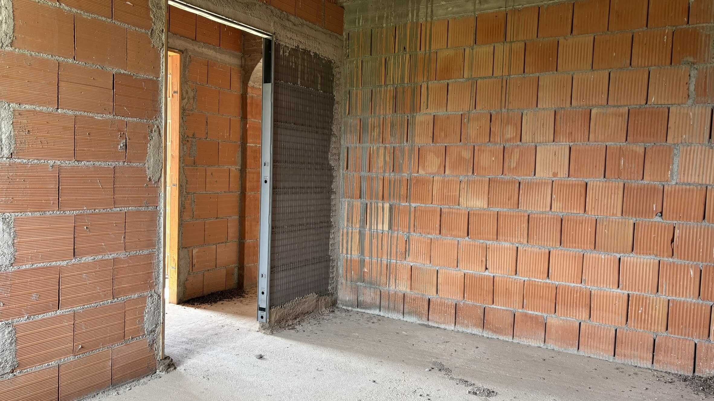 Hal CI0004 - Interno in fase di costruzione con pareti in mattoni rossi e porta metallica, progetto edile NextCasa, ristrutturazione e costruzione immobili, qualità edilizia.