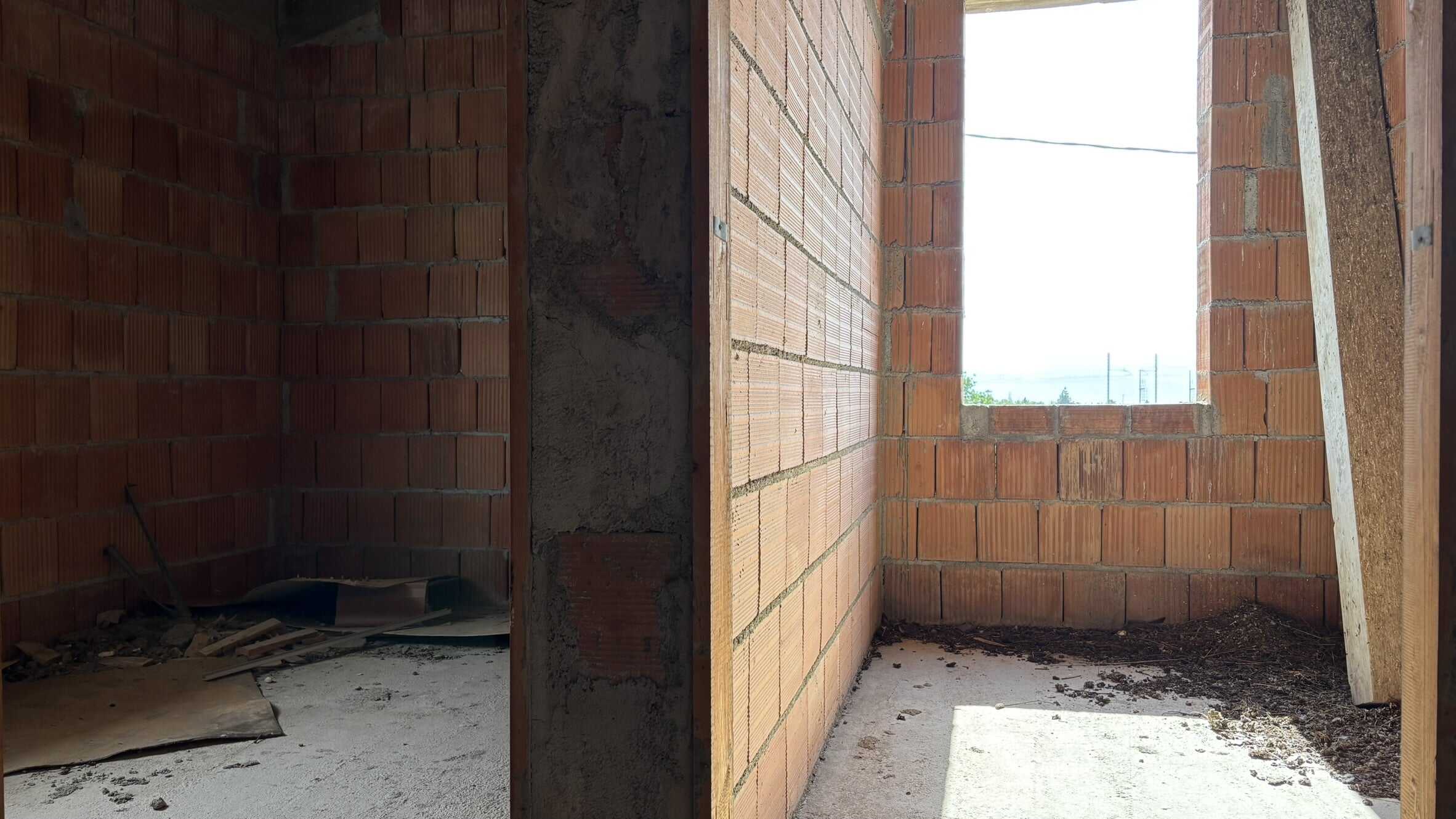 Finestra in costruzione su muri in mattoni rossi, ambiente di lavoro edile, in fase di realizzazione di una casa o edificio, con vista sull'esterno, elementi di edilizia e muratura.