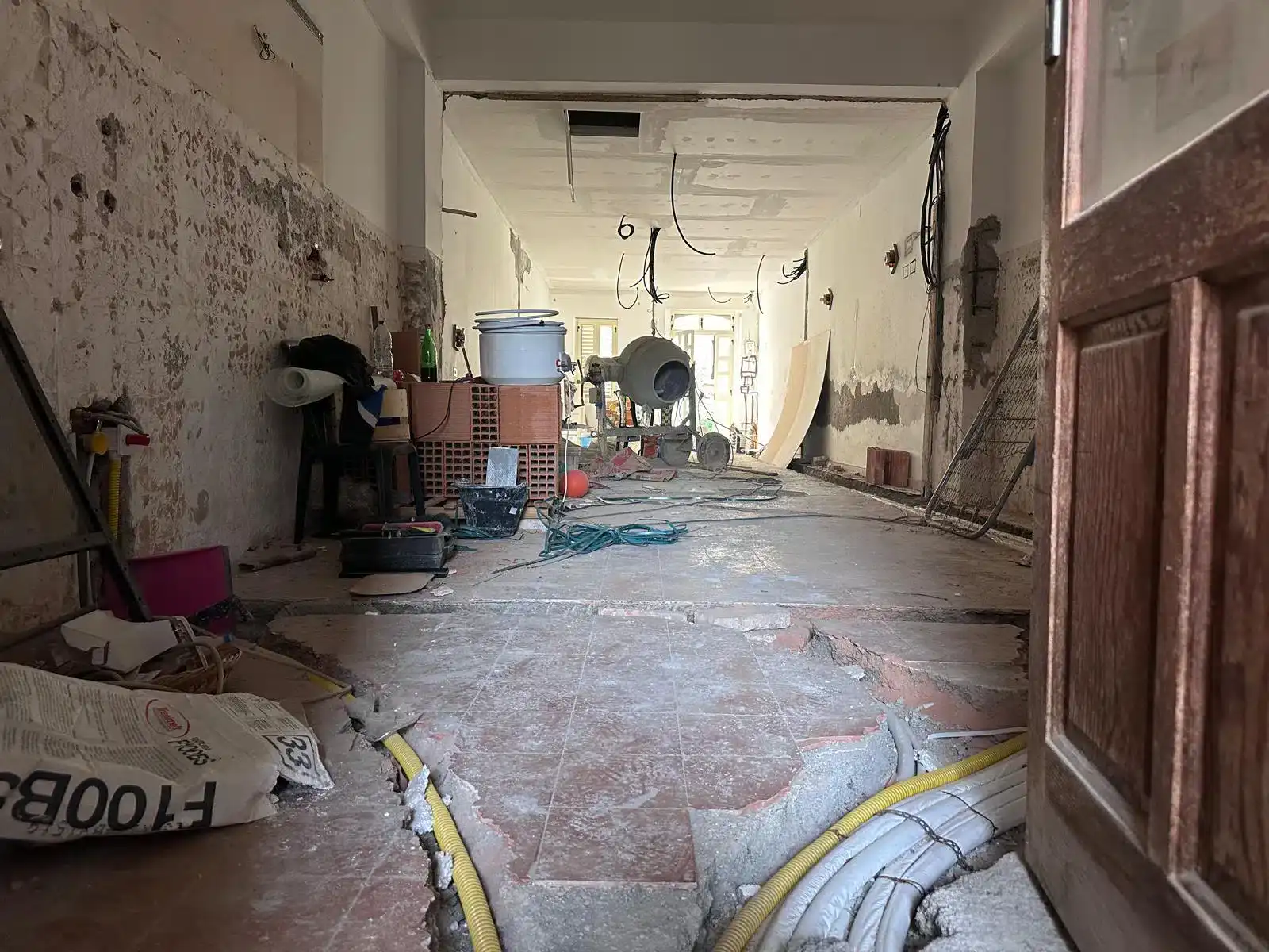 Interno di una casa in ristrutturazione a Milazzo, con lavori in corso, attrezzi e materiali da costruzione visibili.