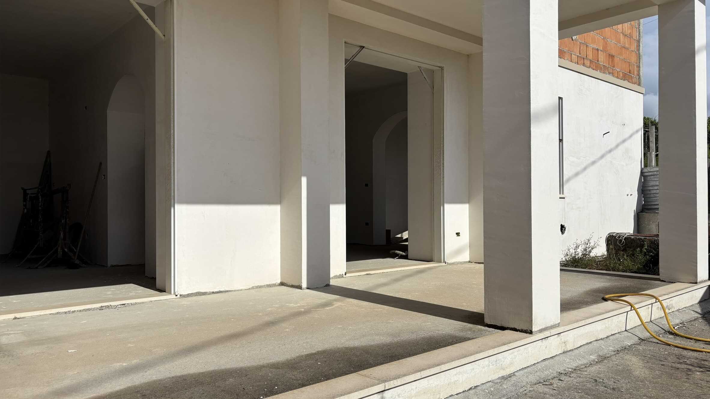 Cantiere edile di nuova costruzione con pareti bianche e strutture in fase di finitura, pronto per essere trasformato in una casa moderna e funzionale.