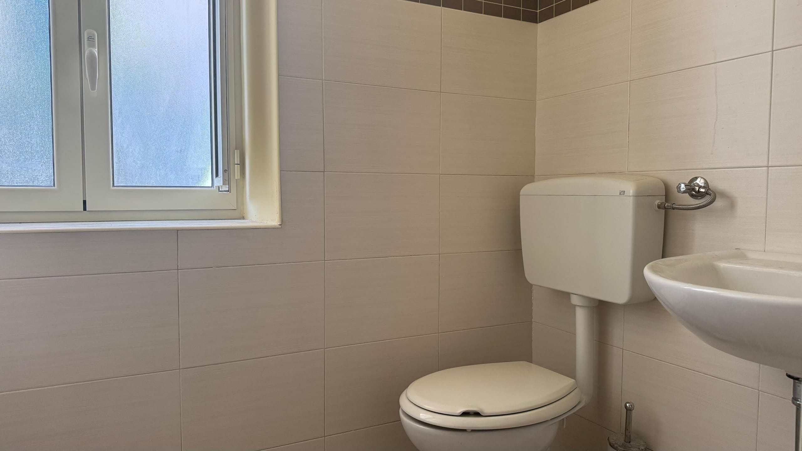 Lavabo e WC in bagno con finestra, dettagli di sanitari moderni, ambiente luminoso e funzionale, ideale per spazi di rinascita e praticità.