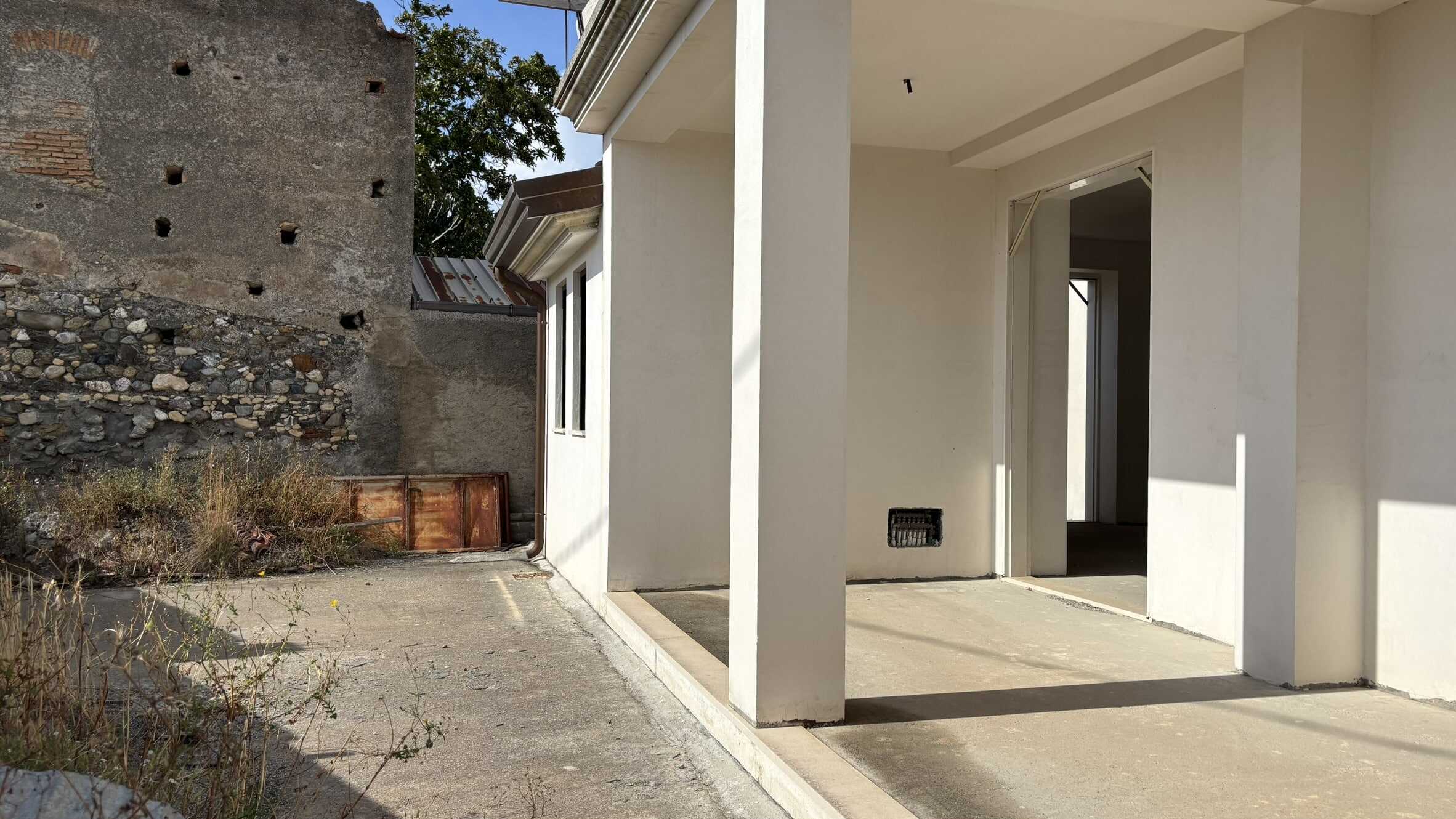 Nuova casa in costruzione con spazio esterno e pareti bianche, ambiente residenziale moderno e luminoso.