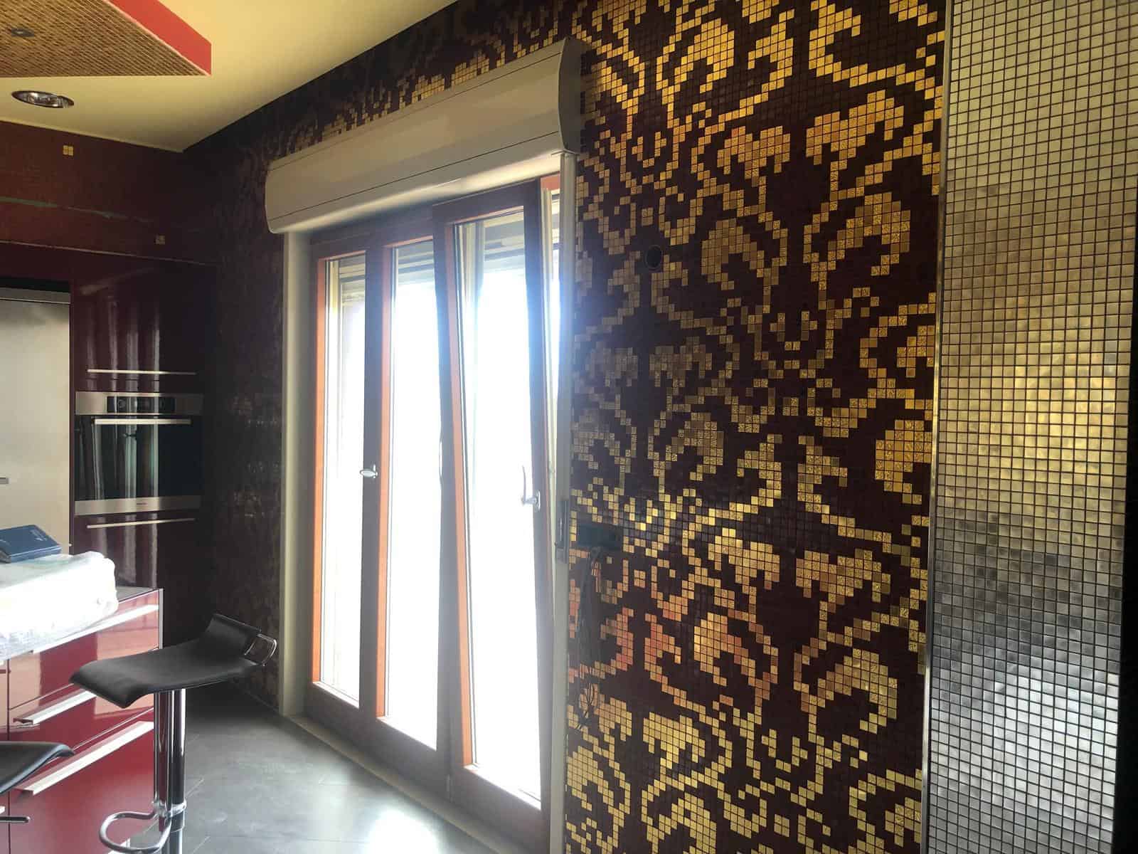 Faldezza in mosaico decorativo nero e oro con dettagli geometrici e floral decor, parete in mosaico e cucina moderna.