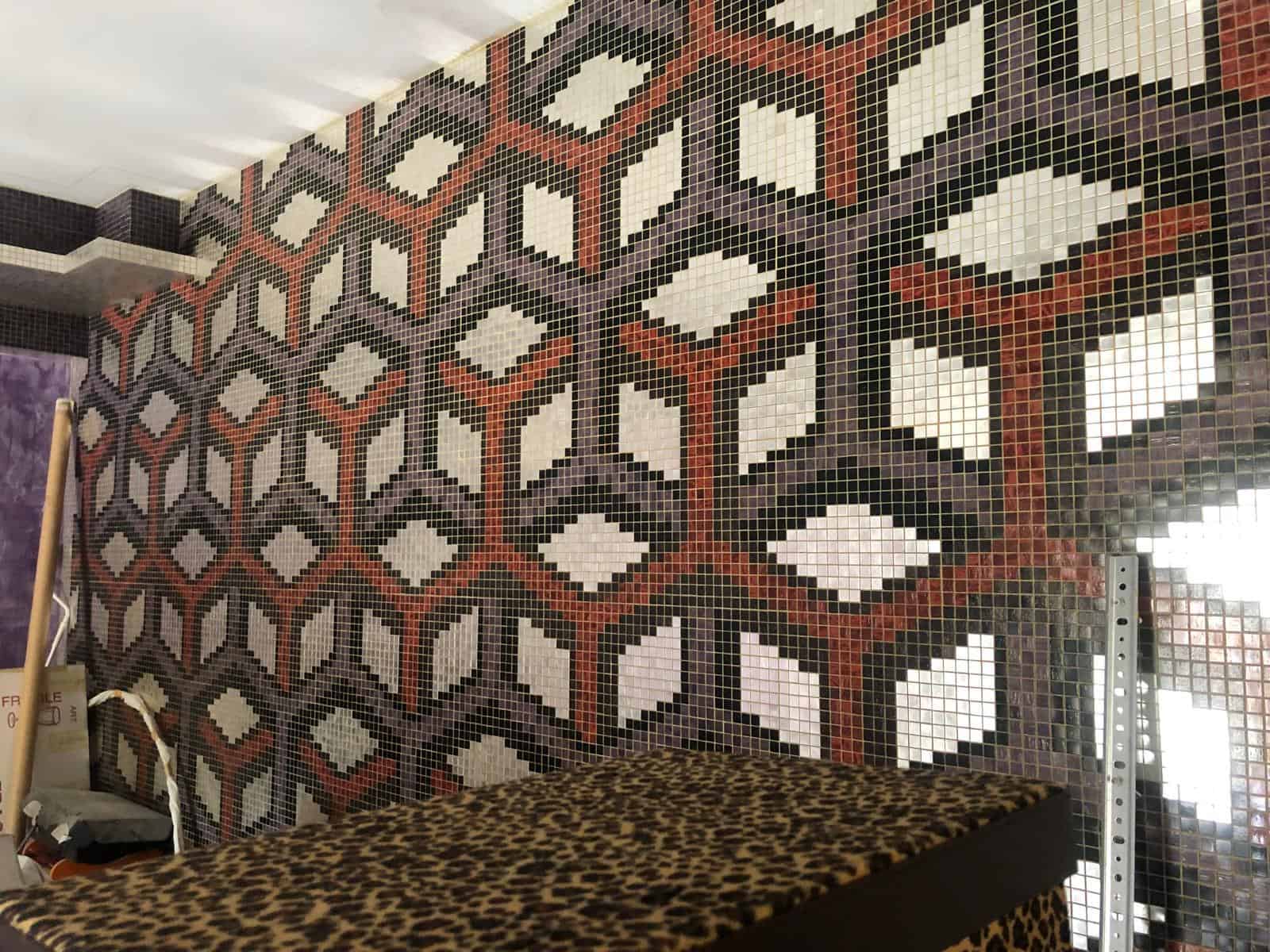 Motivo decorativo in mosaico a parete con geometria colorata nero, bianco e rosso, in stile moderno.
