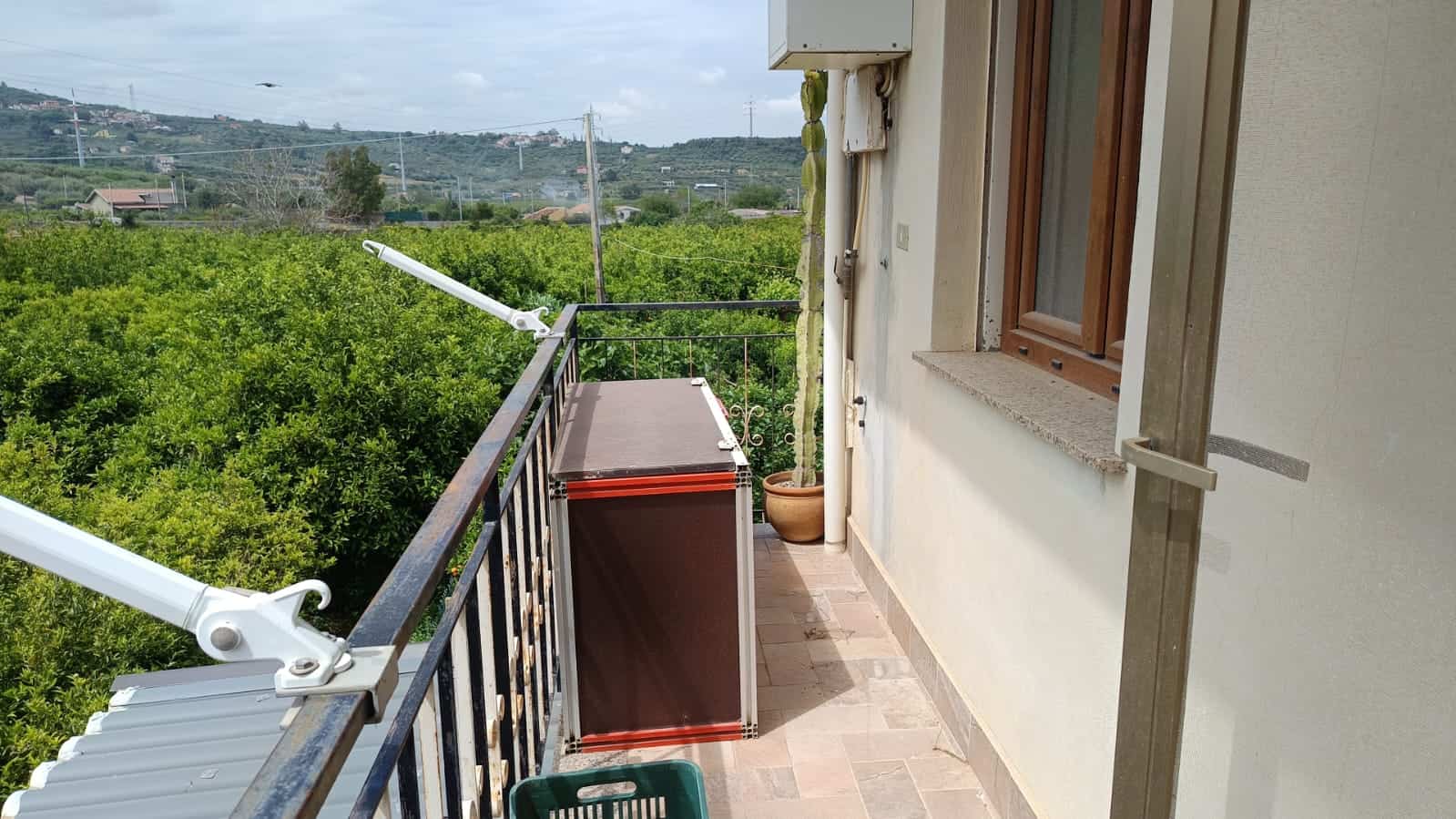 Balcone di appartamento con vista su natura e colline, ideale per relax e godersi l'aria aperta, con spazi per piante e apparecchiature esterne.