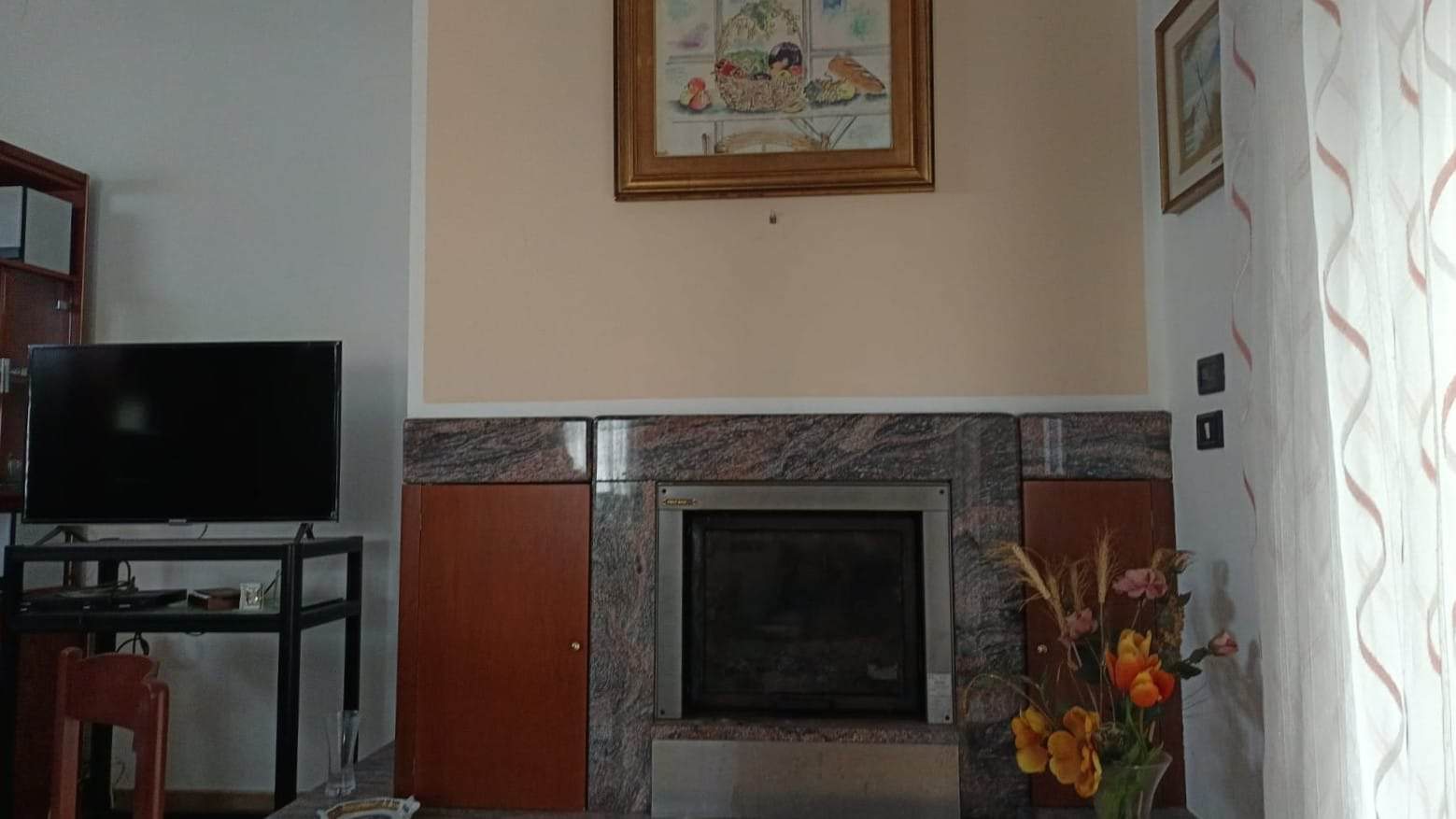 Finestra con tendine leggere e divano decorato con piante e quadri, in una soggiorno elegante e accogliente di una casa NextCasa.