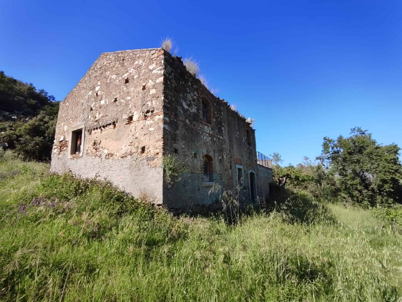 Vecchio edificio rurale in pietra con grande terrazza, immerso nel verde della campagna toscana, ideale per ristrutturazione e realizzazione di casa di charme.