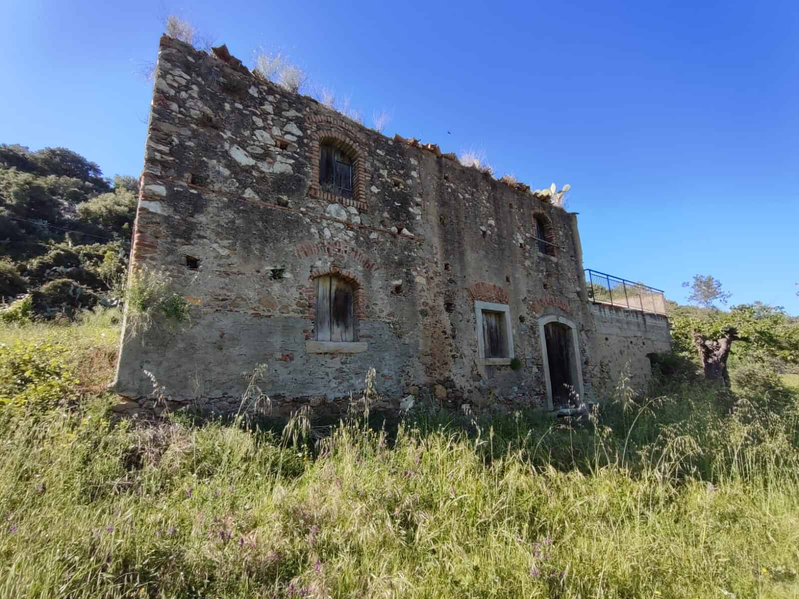 Vecchia casa ristrutturabile in campagna, edificio storico di pietra con finestre in ferro, immerso nel verde e in posizione panoramica, ideale per investimento immobiliare rustico.
