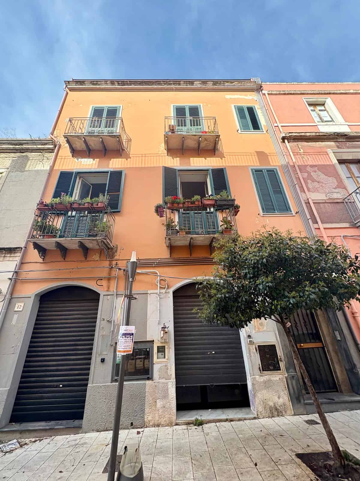 Elegante edificio residenziale in centro città con balconi decorati, facciata colorata e totale esposizione solare, ideale per investimento immobiliare vicino ai servizi urbani.
