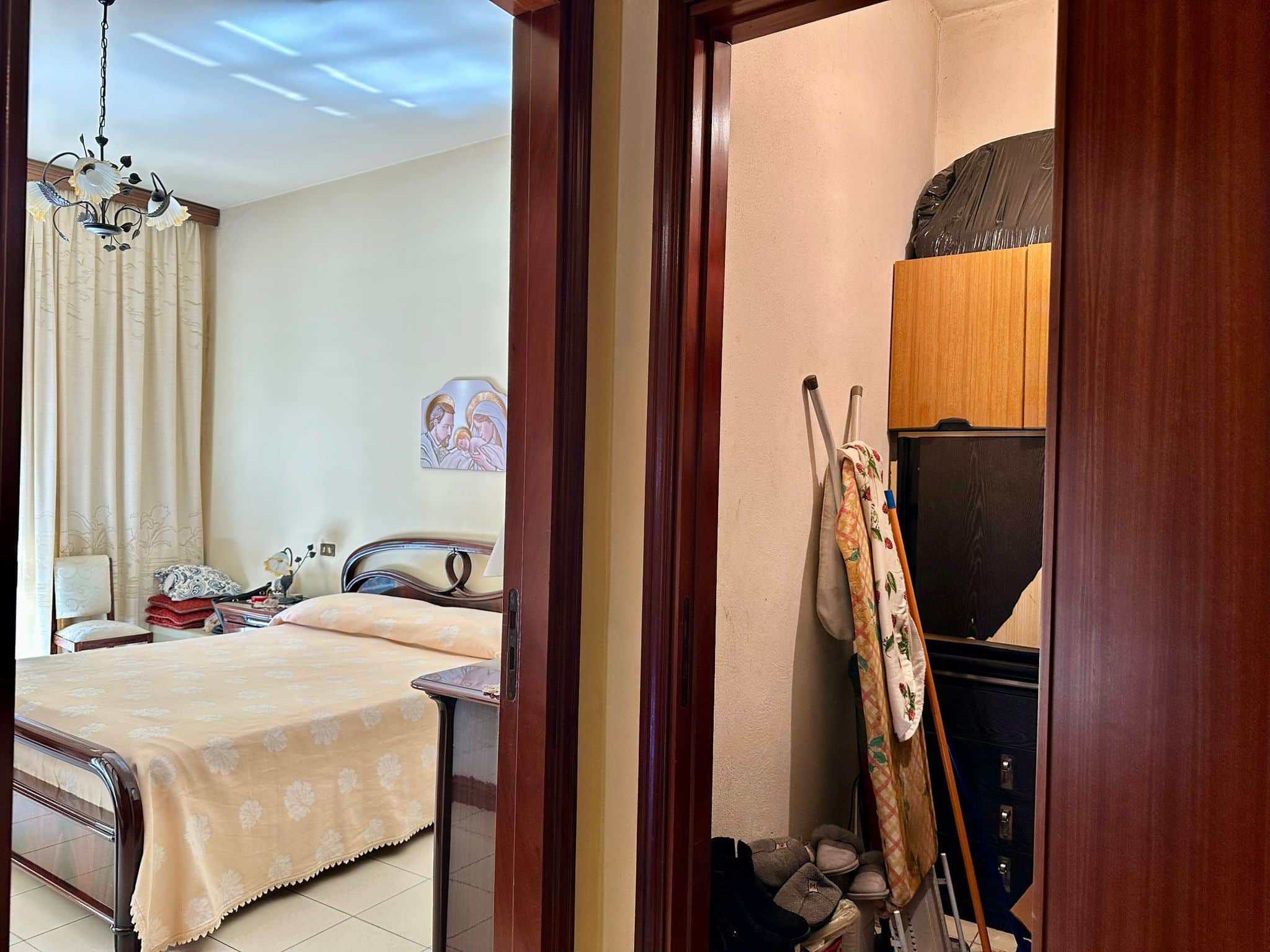Arredamento camera da letto con decorazione classica, lettino, armadio e finestra con tende beige, ambientazione accogliente e luminosa.