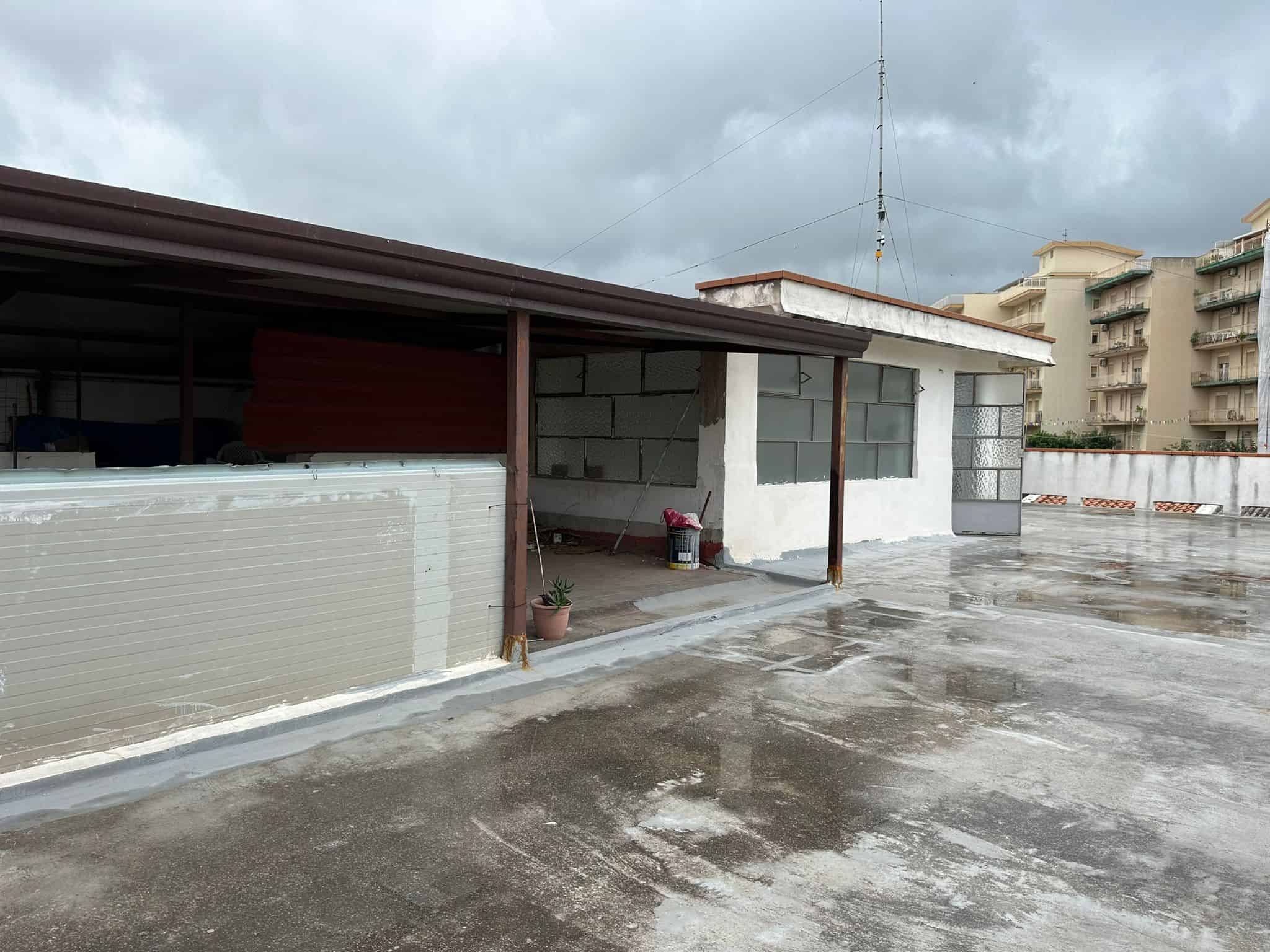 Tetto in fase di rifacimento su terrazza di edificio residenziale, con vista su grattacieli e cielo nuvoloso, progetto di ristrutturazione e manutenzione per immobili in città.