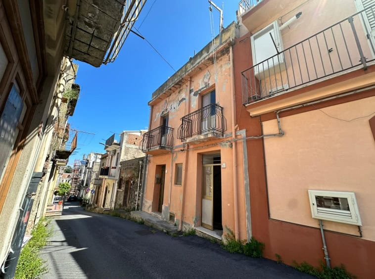 Vecchia casa in stile mediterraneo in un vicolo di un quartiere storico, con pareti colorate, balconi in ferro battuto e finestre piccole, atmosfera autentica e caratteristica.