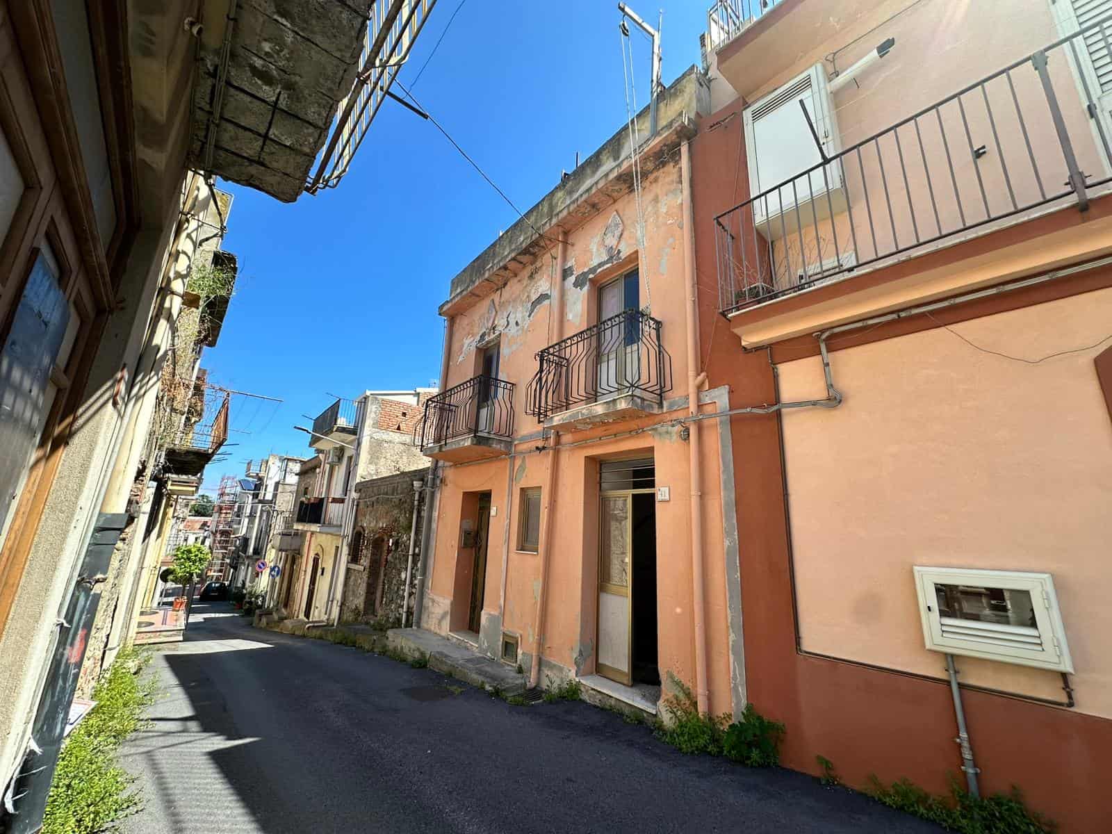 Vecchia casa in stile mediterraneo in un vicolo di un quartiere storico, con pareti colorate, balconi in ferro battuto e finestre piccole, atmosfera autentica e caratteristica.