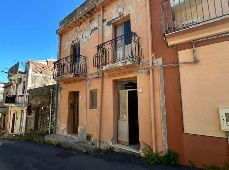 Vecchia casa in stile mediterraneo con facciata colorata e balconi in ferro battuto, zona residenziale soleggiata e da ristrutturare, ideale per investimento immobiliare o progetto di recupero edilizio.