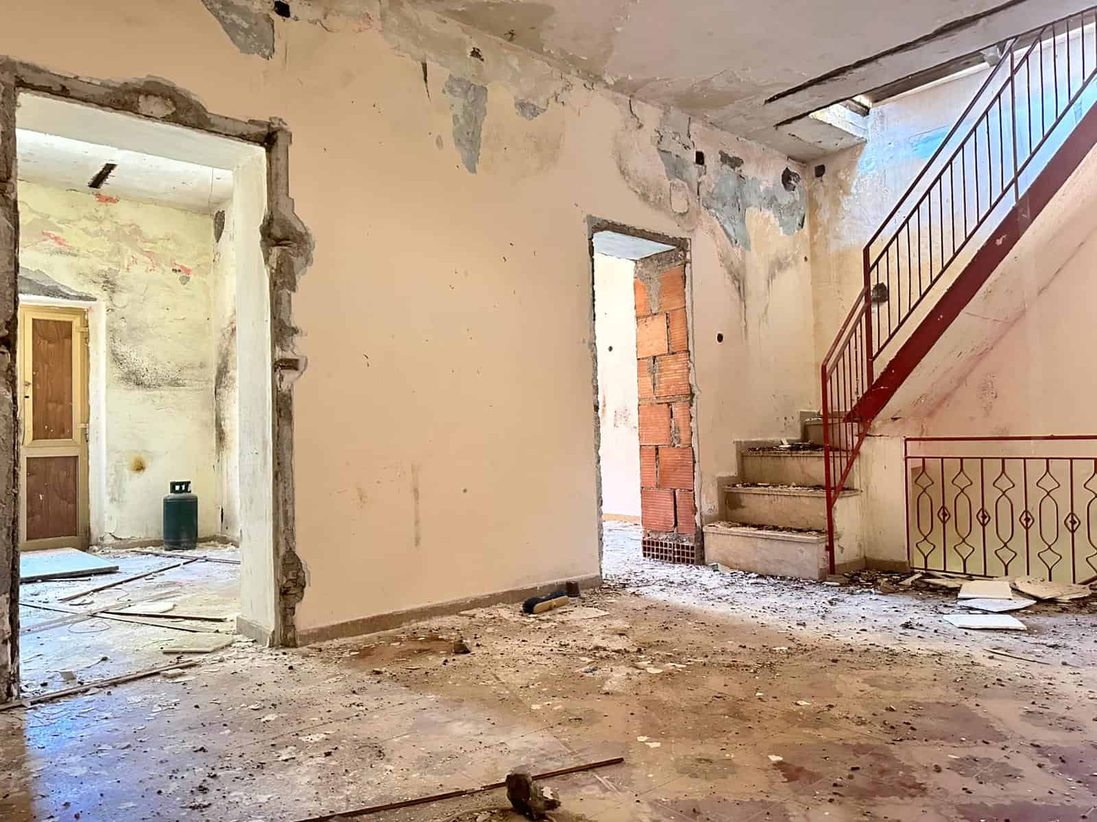 Immagine di un interno in fase di ristrutturazione di una casa con muri sconnessi e pavimento sporco, pronto per lavori di ristrutturazione, ideale per progetti di ristrutturazione immobili su NextCasa.