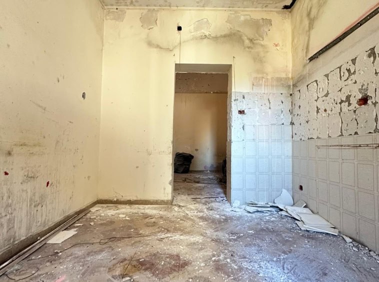 Finitura di un interno in ristrutturazione, pareti sbiadite e pavimento in gres porcellanato usurato, spazio in attesa di ristrutturazione o personalizzazione.