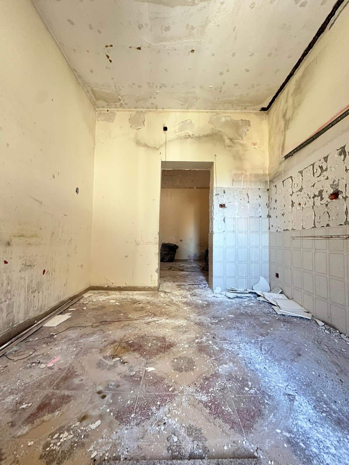 Finitura di un interno in ristrutturazione, pareti sbiadite e pavimento in gres porcellanato usurato, spazio in attesa di ristrutturazione o personalizzazione.