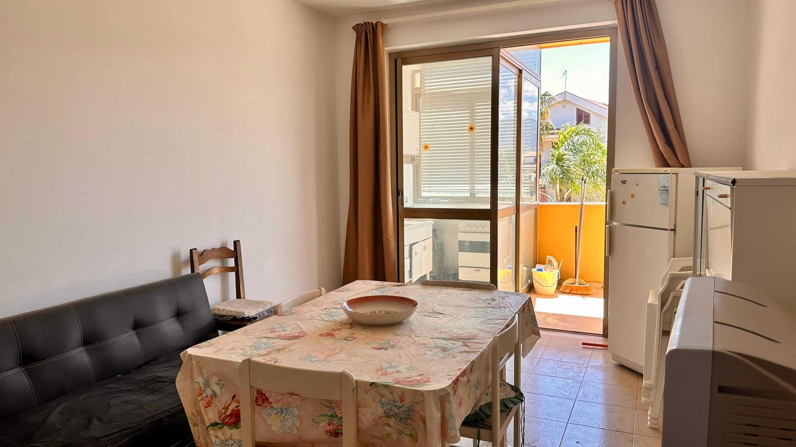 Finestra sulla terrazza con vista su case e piante tropicali, ambiente luminoso e accogliente.