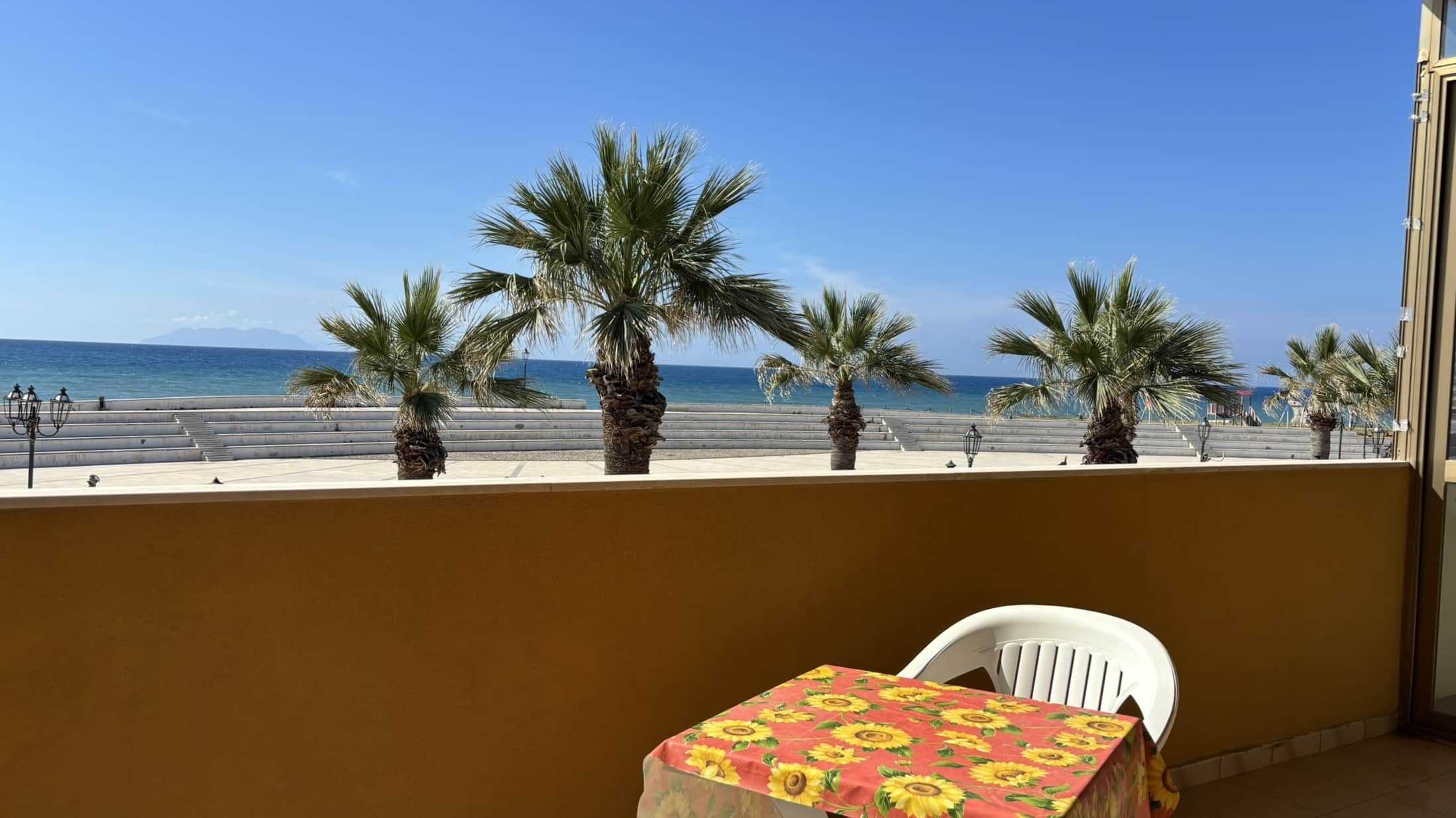 IMG_4417 Vivid seaside view with palm trees and clear blue sky, perfect for enjoying relax in a beachfront apartment at NextCasa in Italy.