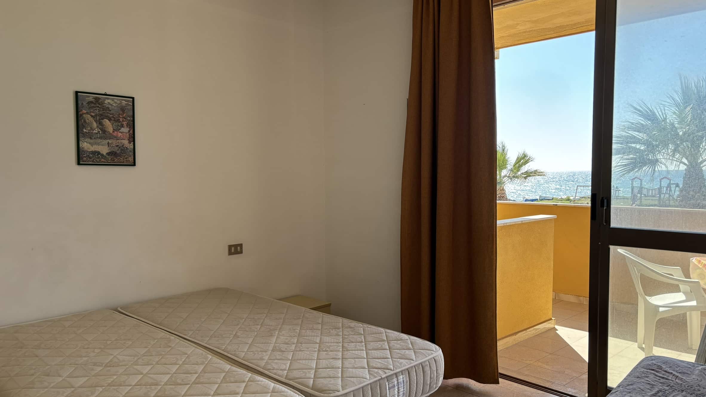 Letto matrimoniale con vista mare e accesso al balcone in una camera di NextCasa, struttura emergente per affitti turistici a Jesolo.