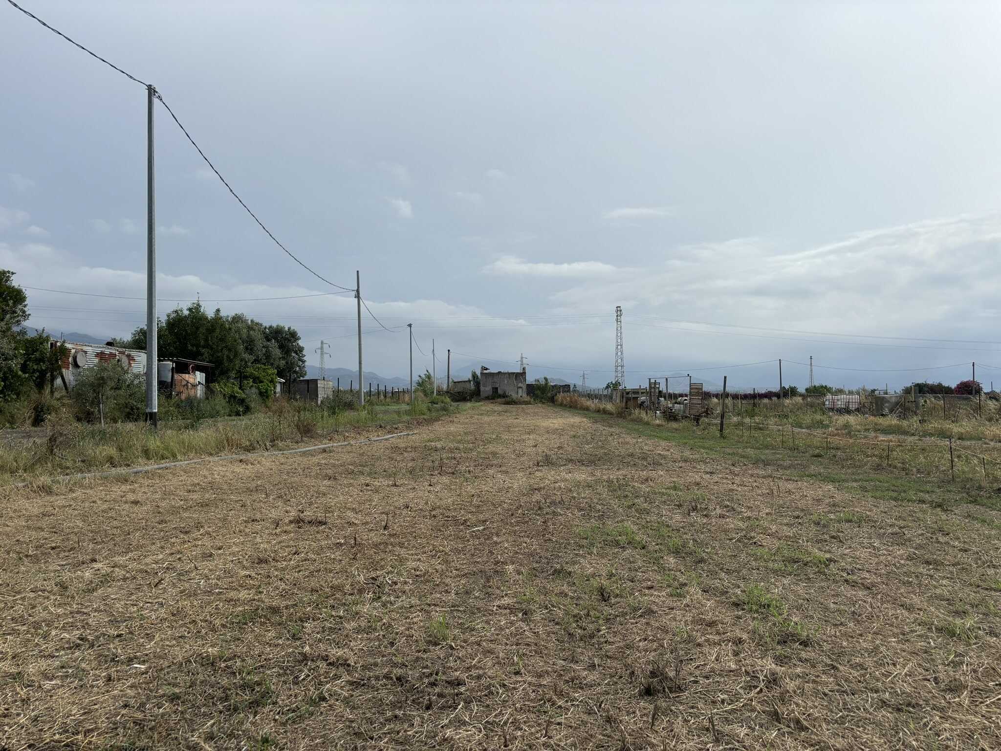 Terreno agricolo in vendita in campagna, ampio spazio aperto con vista su montagna e cielo nuvoloso, ideale per costruire casa o attività all'aperto.