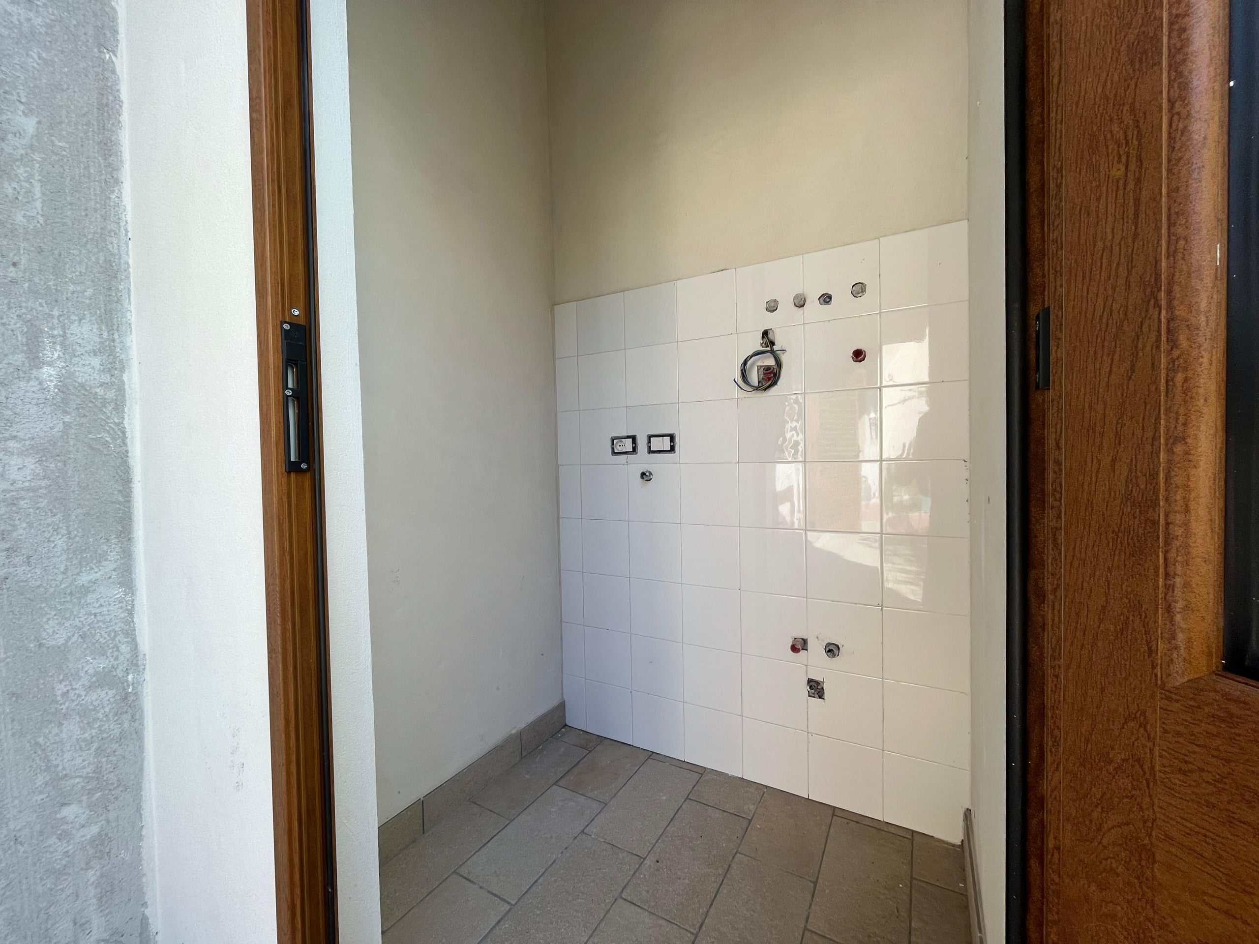 Ristrutturazione cucina open space, pareti bianche, pavimento in piastrelle beige, impianto idraulico e elettrico in fase di installazione, ambienti moderni e funzionali.