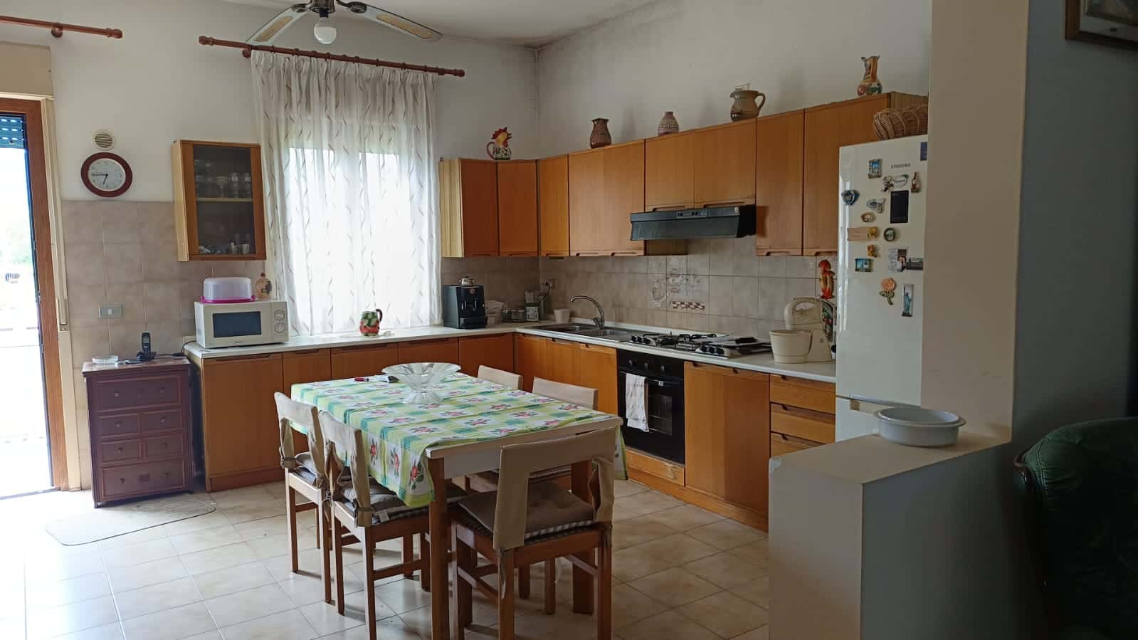 Antico soggiorno con cucina funzionale e dettagli rustici, mobili in legno, elettrodomestici moderni e atmosfera accogliente, ideale per servizi immobiliari e affitti vacanze.
