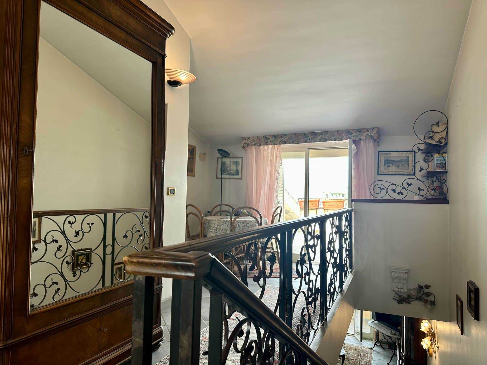 Ampio soggiorno con balcone e ringhiera in ferro battuto, arredamento rustico e decorazioni classiche in stile, illuminazione naturale, ideale per case di lusso o appartamenti di charme.