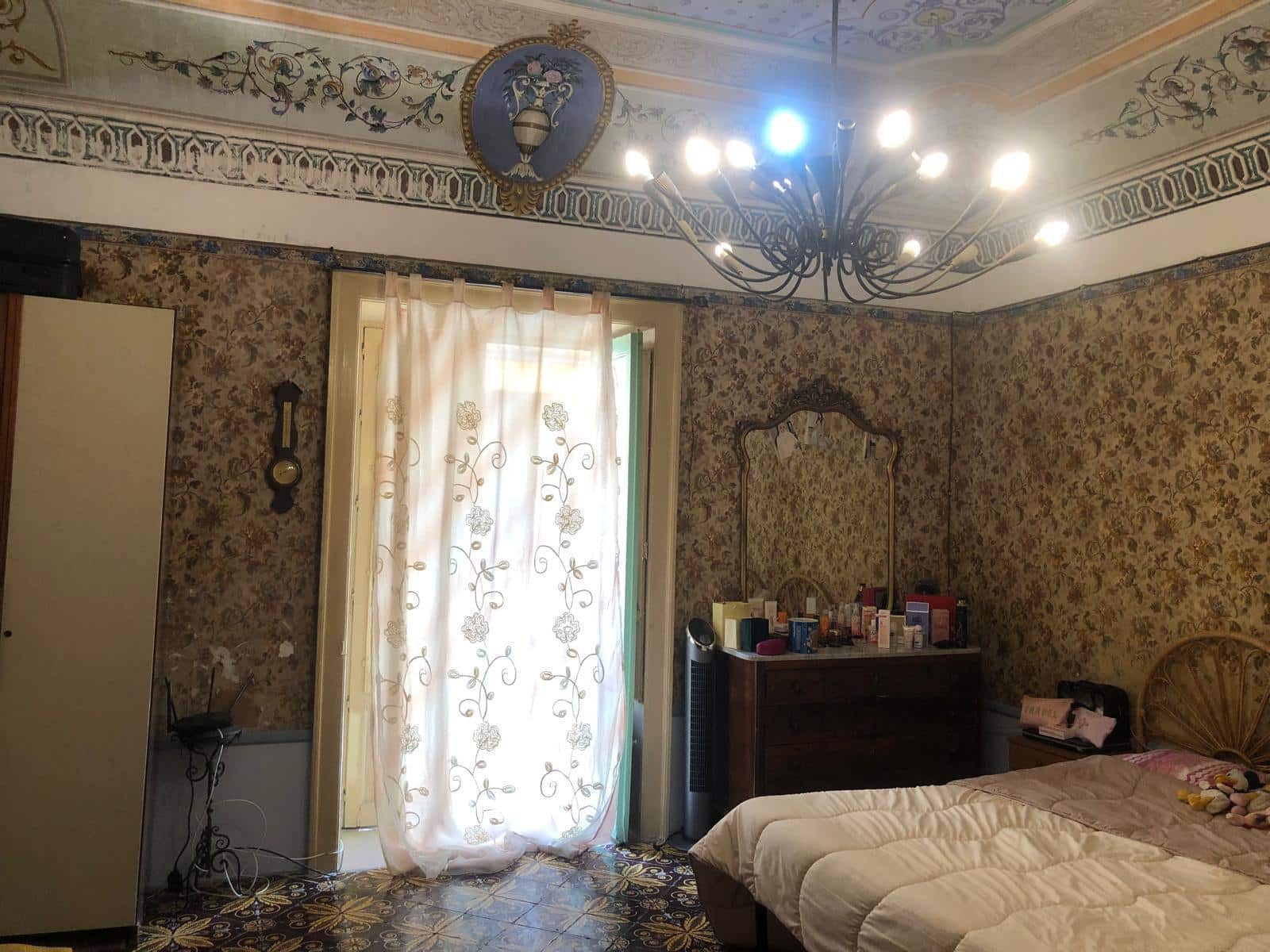 Affresco classico, camera da letto con arredi vintage, ambiente eleganti e accogliente, illuminazione centrale, tende decorative, mobili d'epoca, stile raffinato e ricercato, perfetto per appassionati di arredamento d'epoca.