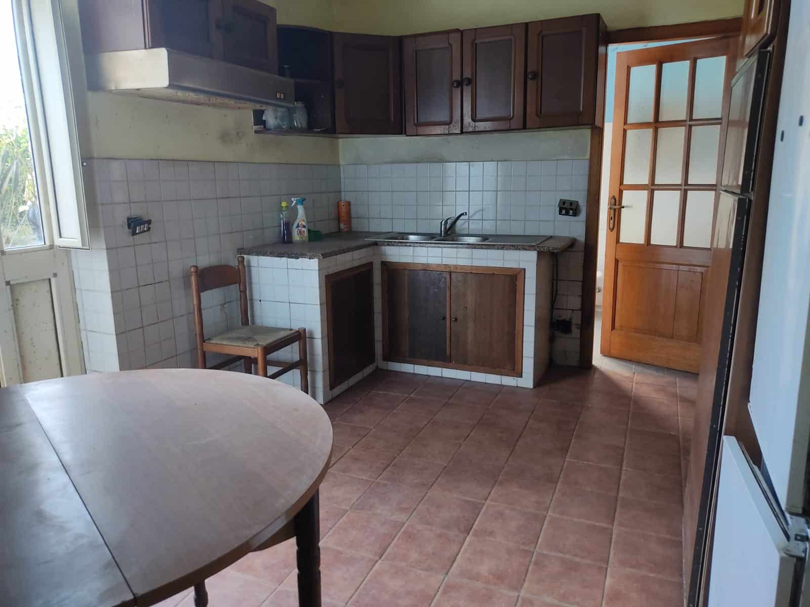 Cucinotto con ante in legno, piano in granito, forno, lavabo e balcone, arredato in stile semplice e funzionale, ideale per le esigenze quotidiane della casa.