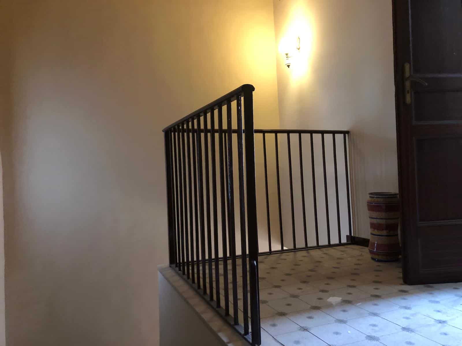 Scalinate in ferro battuto per interni casa, corrimano elegante e sicuro, ambiente luminoso con parete beige e lampada, pavimento in ceramica decorata, arredo rustico vicino ad un mobile in legno grosso, stile classico e accogliente, ottimo per appartamenti e case di charme, complementi di arredo di alta qualità, soluzioni di design innovative per la casa.