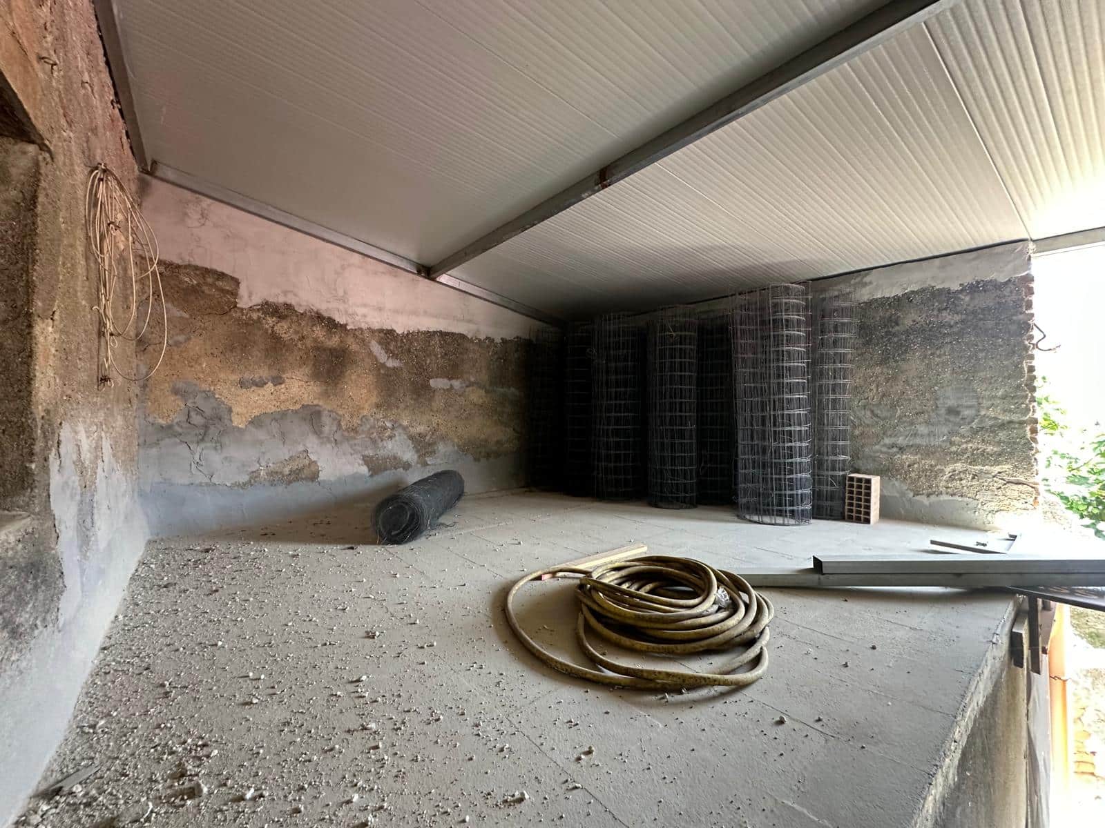 Fondo cantiere edile con pareti in cemento e struttura in metallo, materiali da costruzione e tubi di plastica sul pavimento.