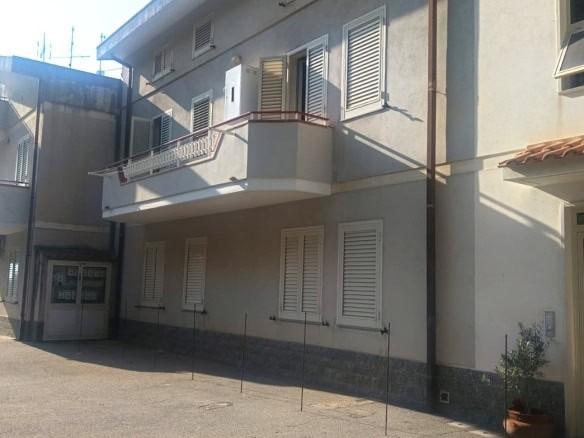 Finestra con persiane bianche e balcone in edificio residenziale a due piani nel quartiere urbano.