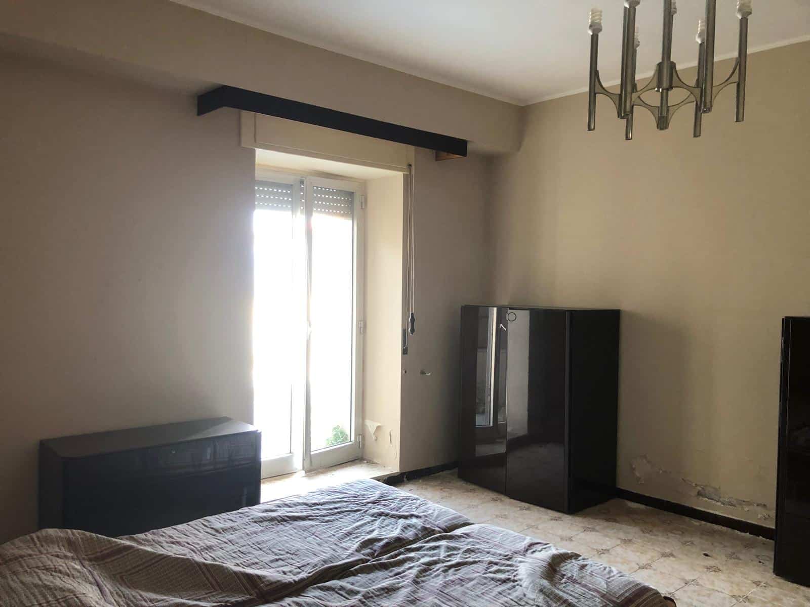 Spazio soggiorno primi piani, camera matrimoniale con mobilio nero, luce naturale, occasione immobiliare in Italia, NextCasa.