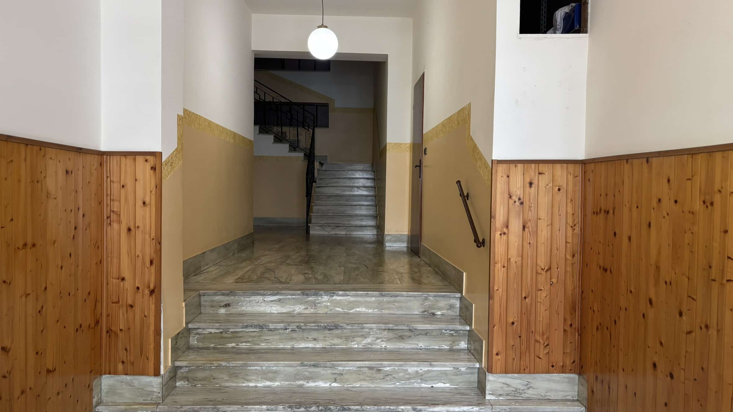 Scaleggia con ringhiera in ferro battuto e pareti dipinte in colori caldi.