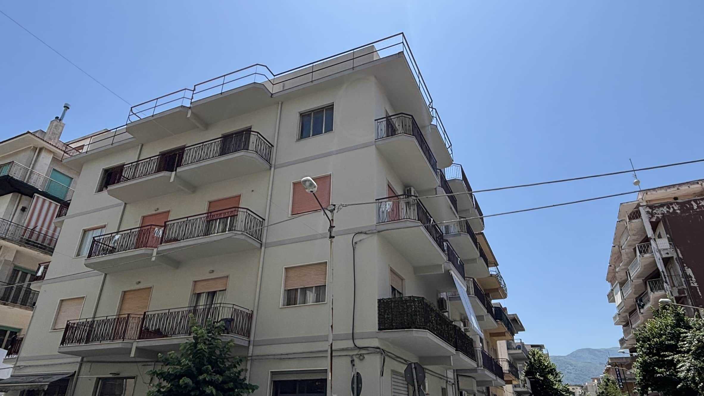 Faro di appartamento residenziale con balconi in zona urbana, edificio moderno, contesto cittadino con montagne sullo sfondo, cielo sereno, struttura di nuovo design, investimento immobiliare, NextCasa.
