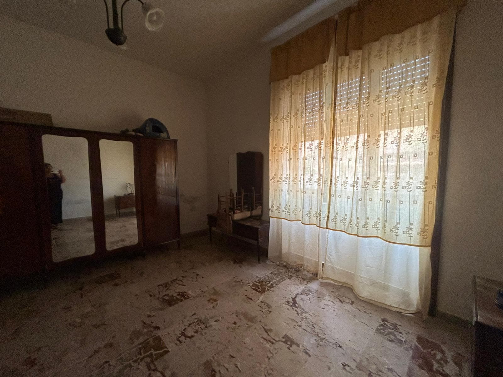 Armadio antico in legno con ante a specchio e tende beige con ricami, stanza da letto tradizionale, arredamento vintage, pavimento in marmo, atmosfera calda e accogliente, casa NextCasa.