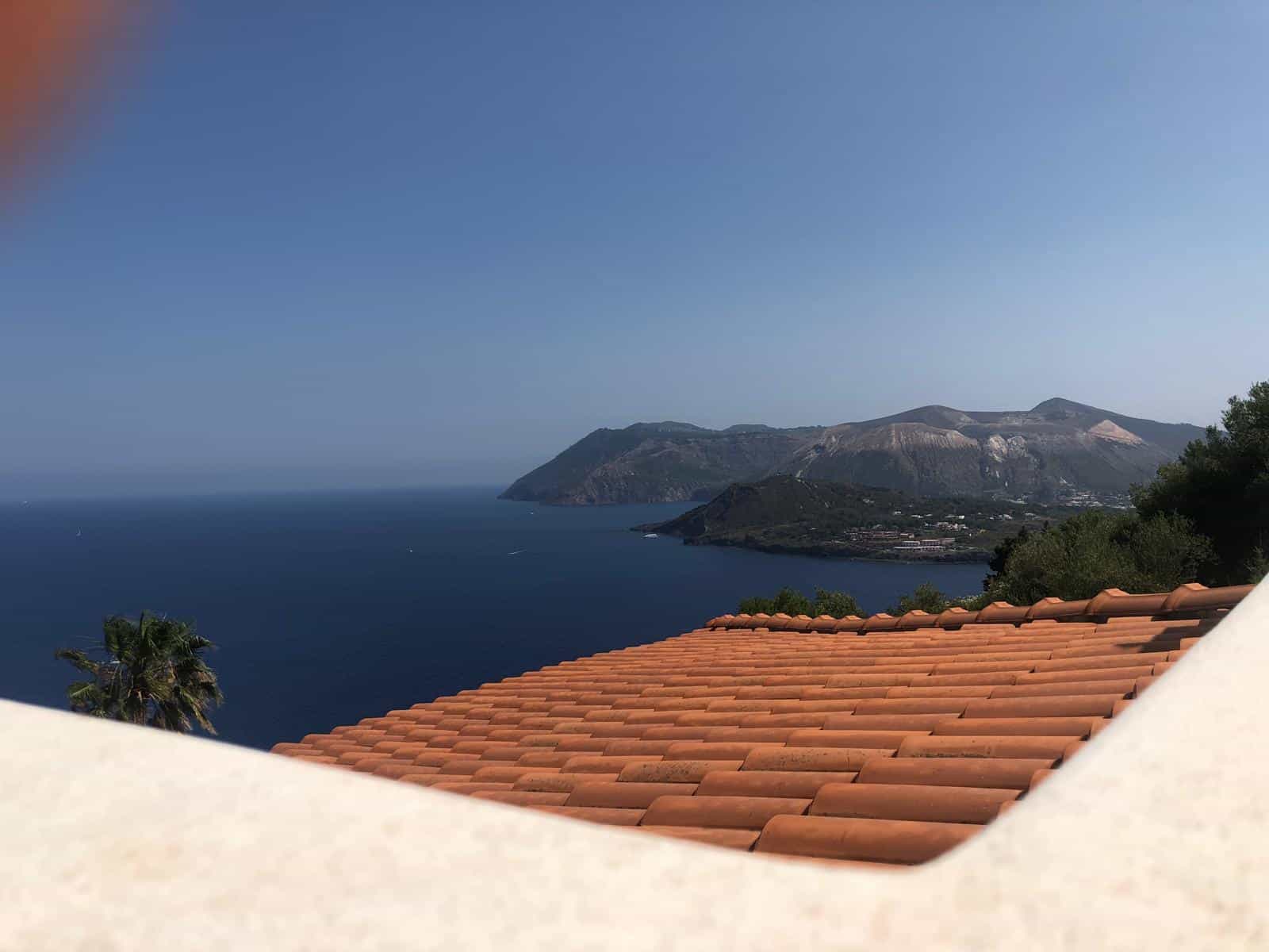 Vista panoramica del mare e delle montagne del Vesuvio con tetto in terracotta in primo piano, in un contesto di immobile residenziale sul mare a Positano, Costiera Amalfitana, Italia.